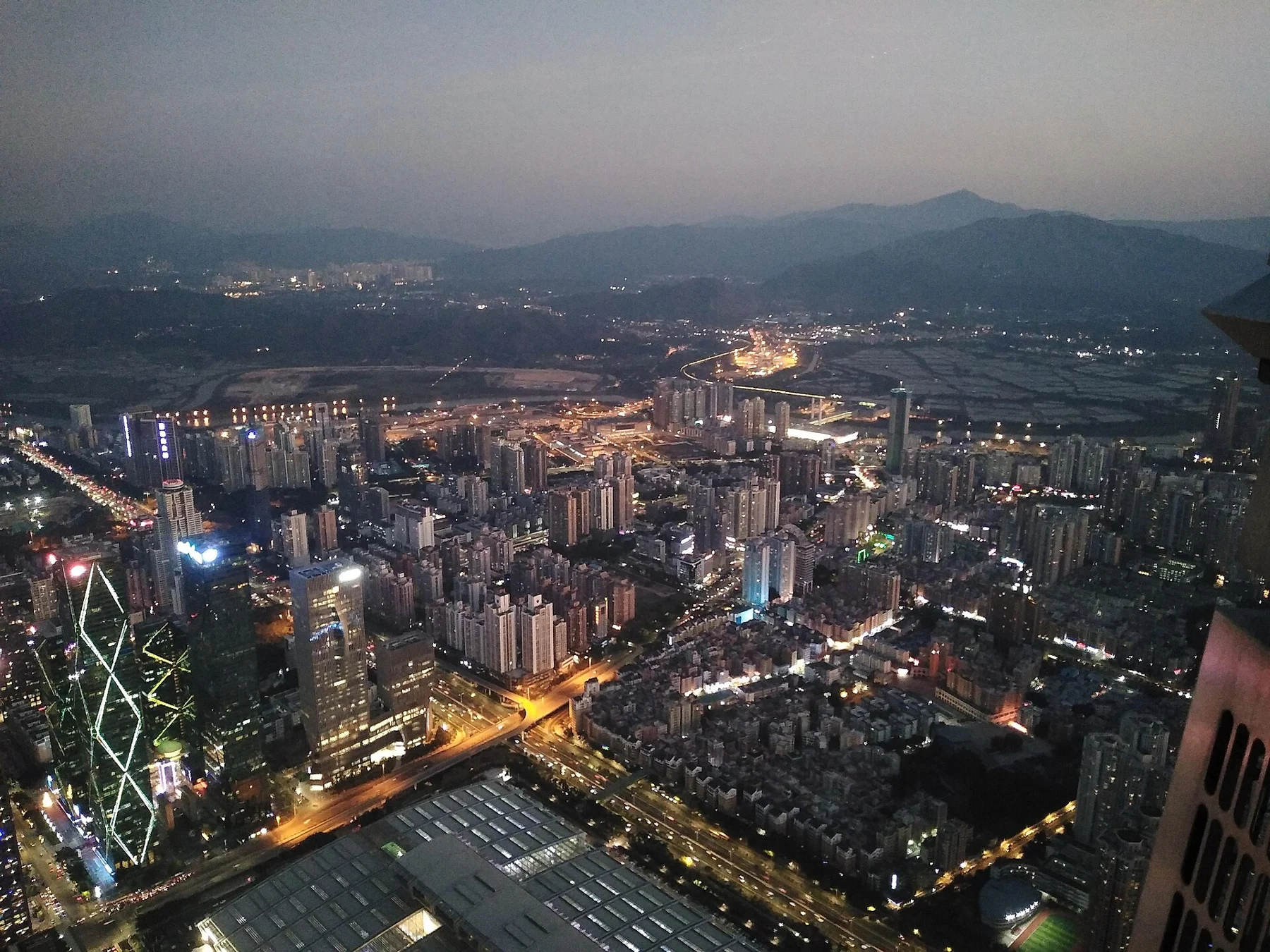 Lit roads and buildings below a blue evening sky.