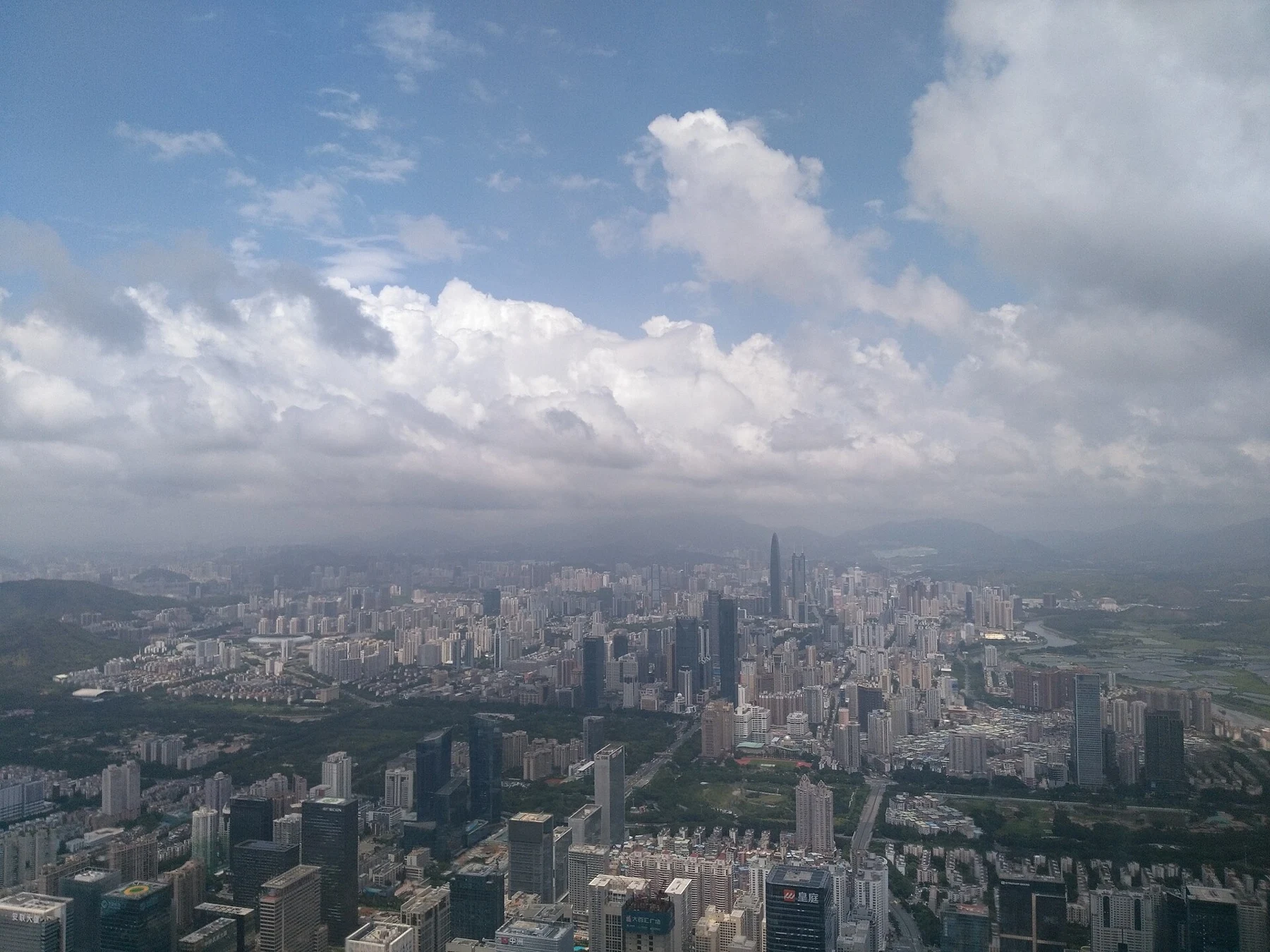 Tall bright clouds above a wide Shenzhen skyline.