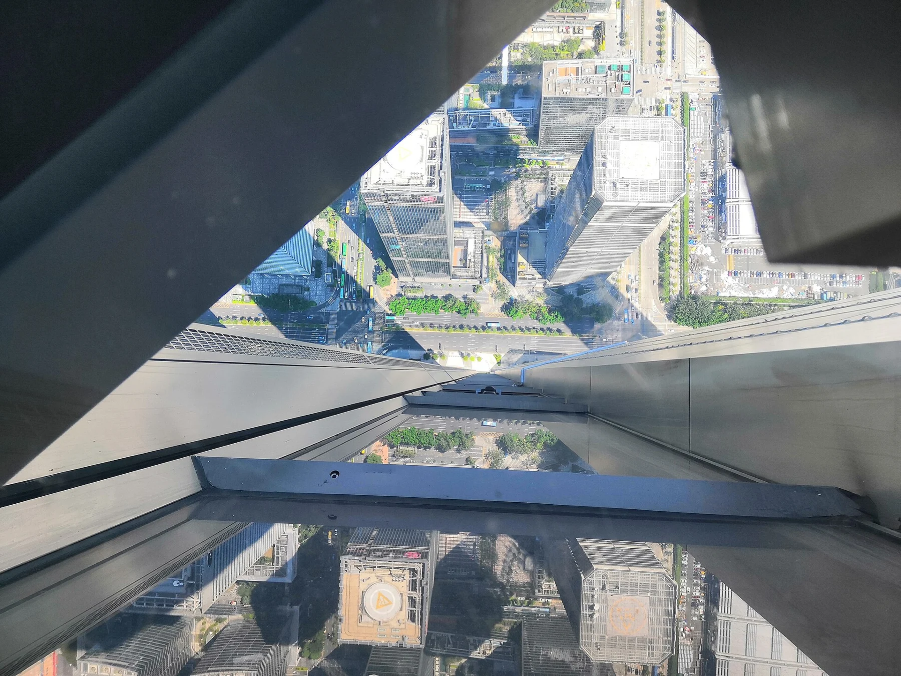 Diagonal structural framing surrounds a downward view of towers and roads.