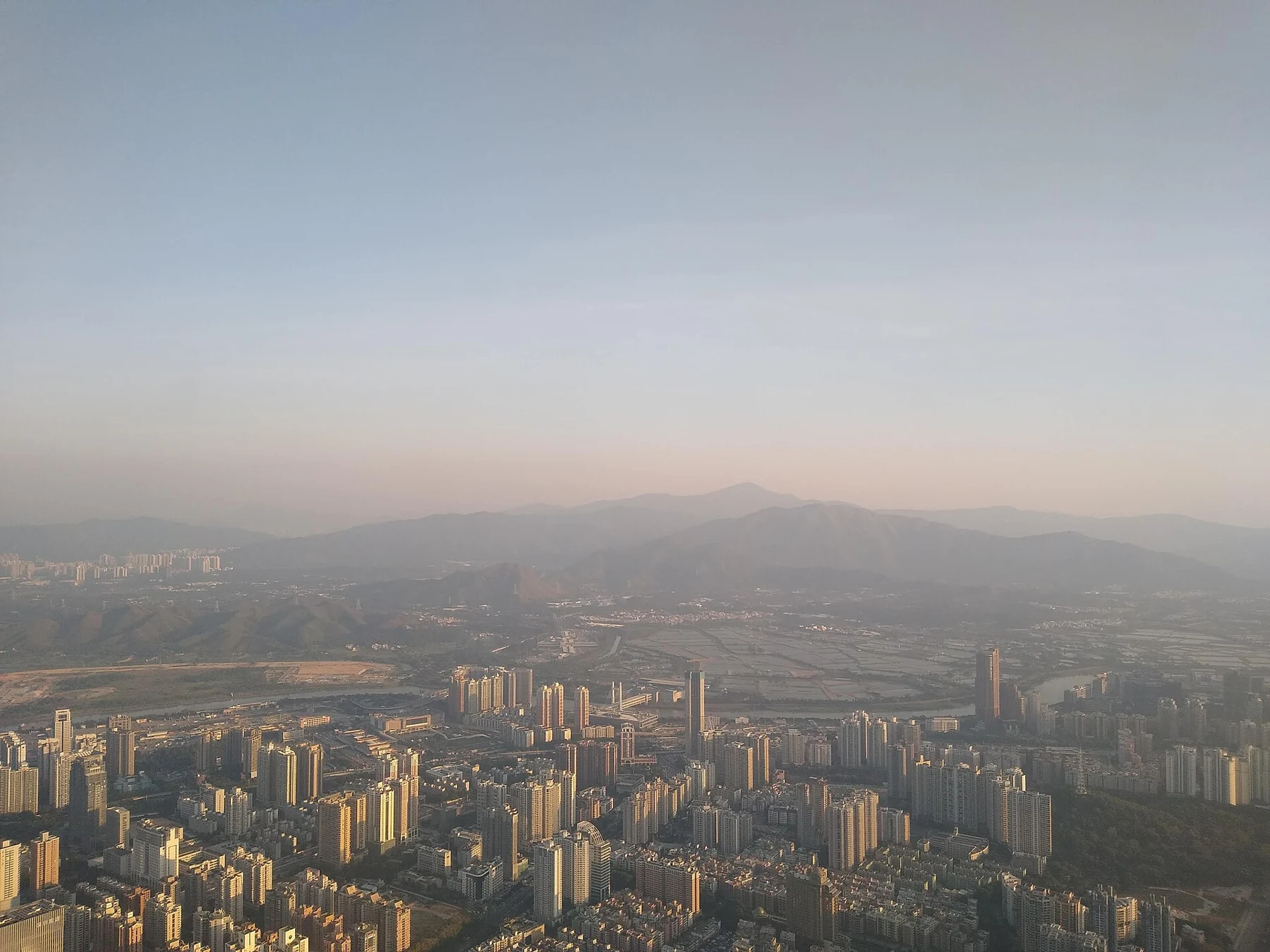 City buildings fade into hazy hills beyond the observatory window.