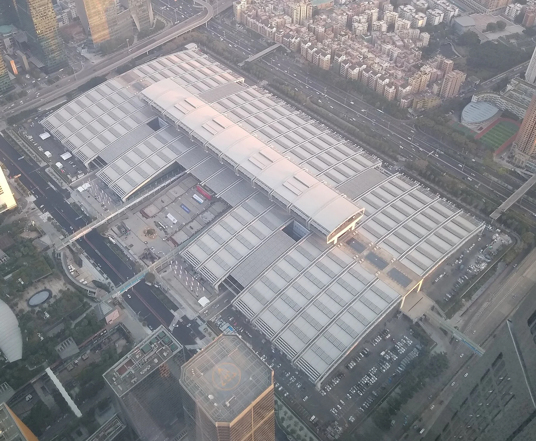 Broad exhibition-hall roofs and surrounding roads viewed from high above.