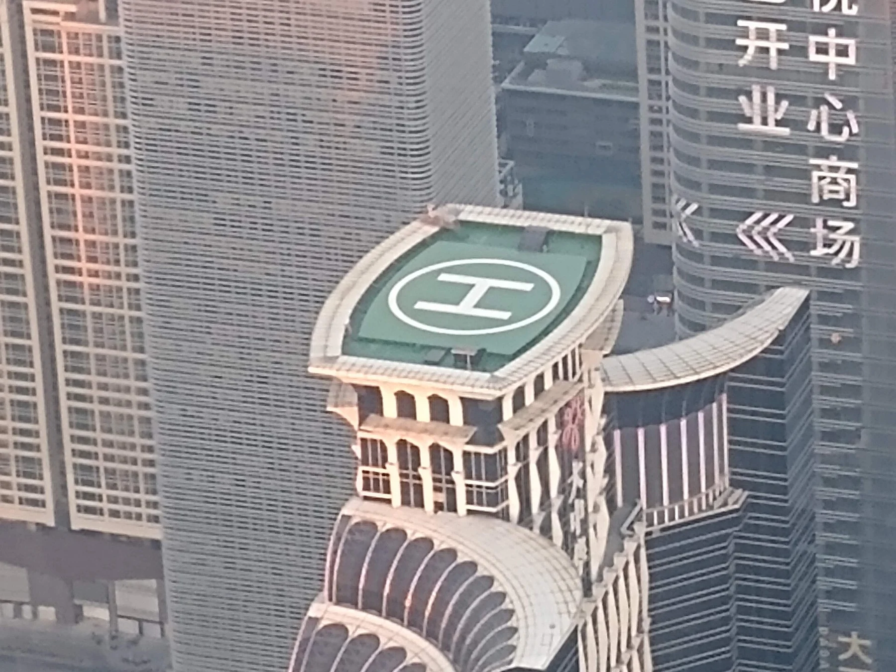 A nearby tower rooftop with a circular H marking seen from above.