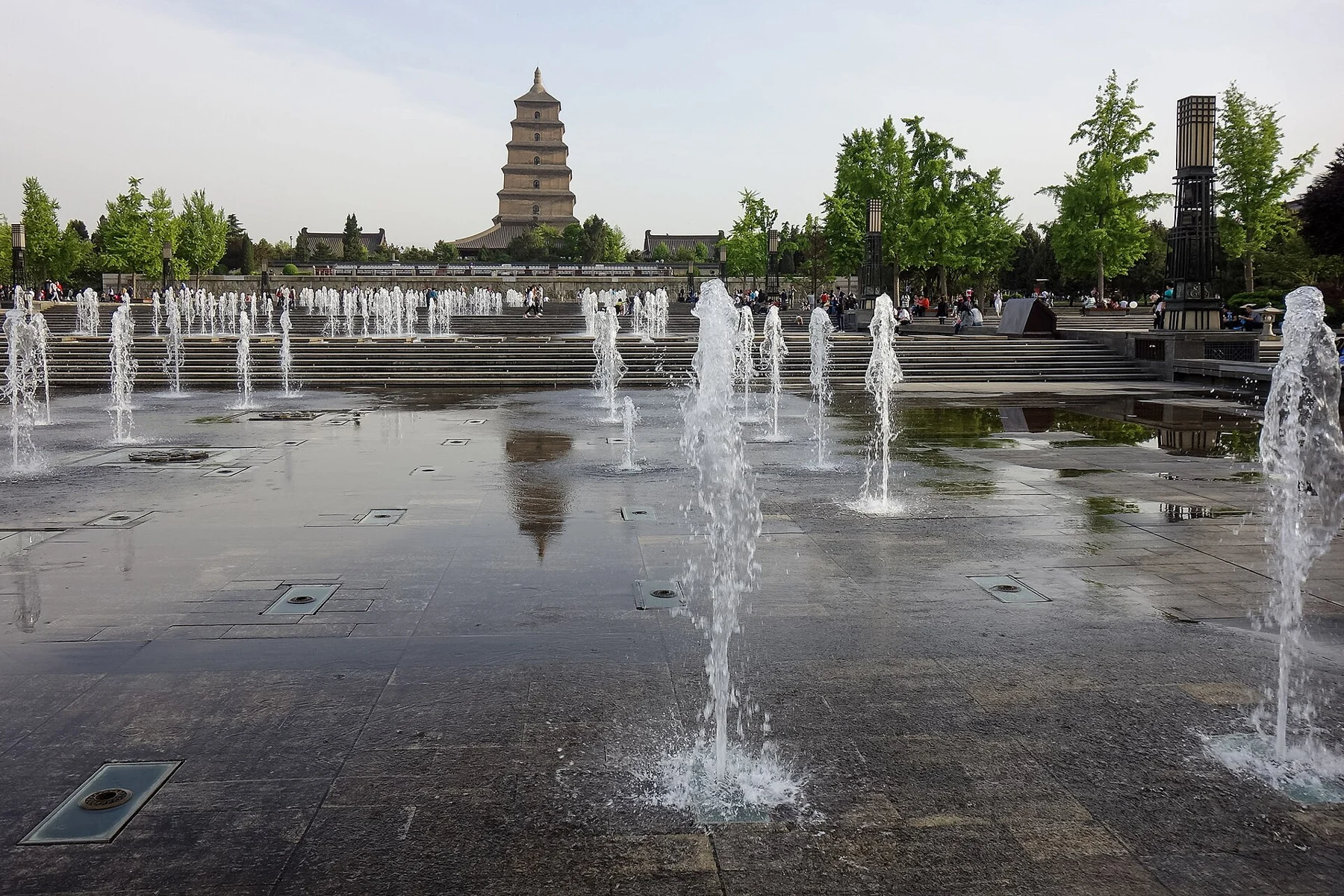 Low fountains and broad water pools in the North Square with the pagoda in the distance.