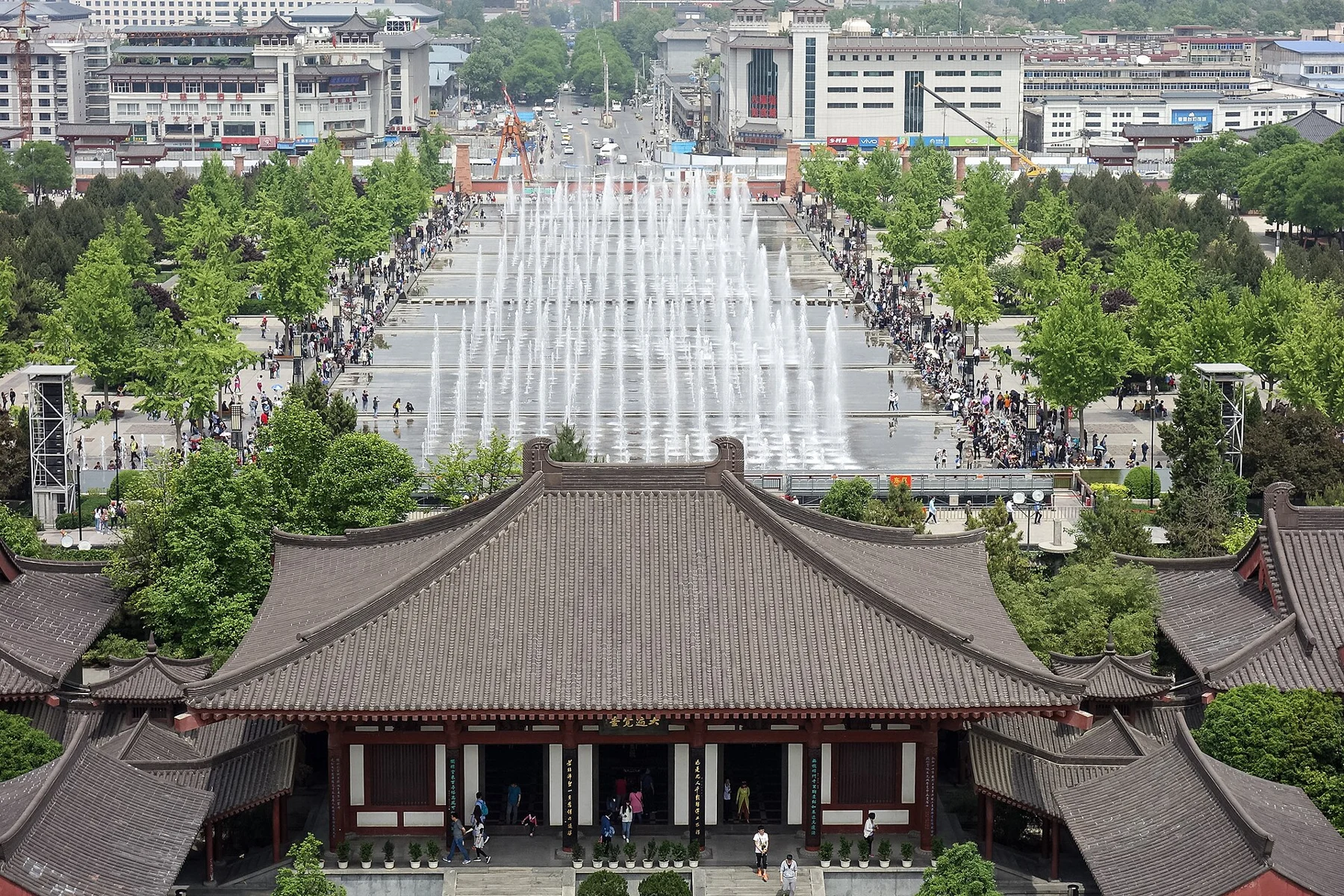 Elevated view over a temple roof towards the stepped pools and fountains in the North Square.