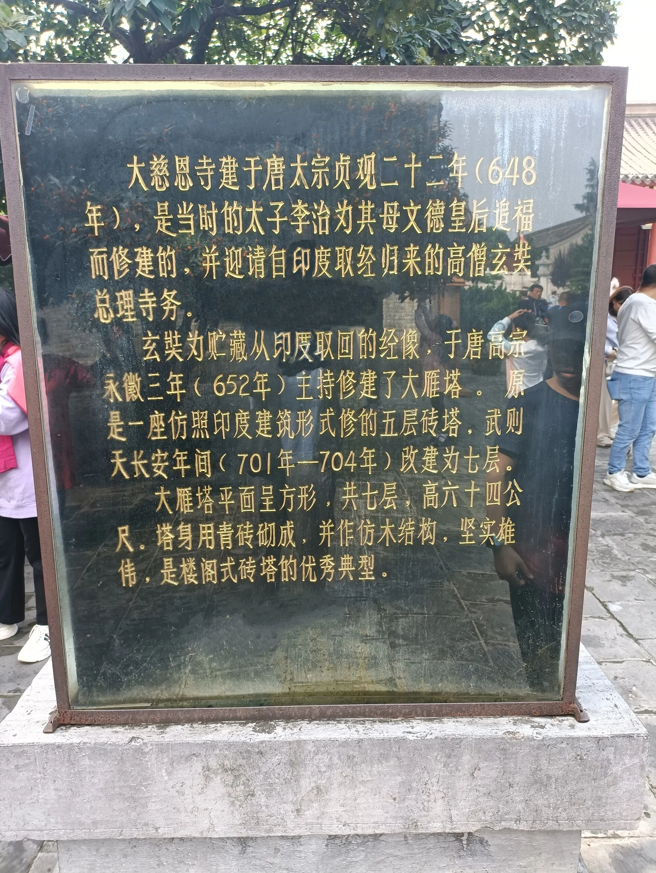Gold Chinese historical text on a dark information stone at the pagoda.