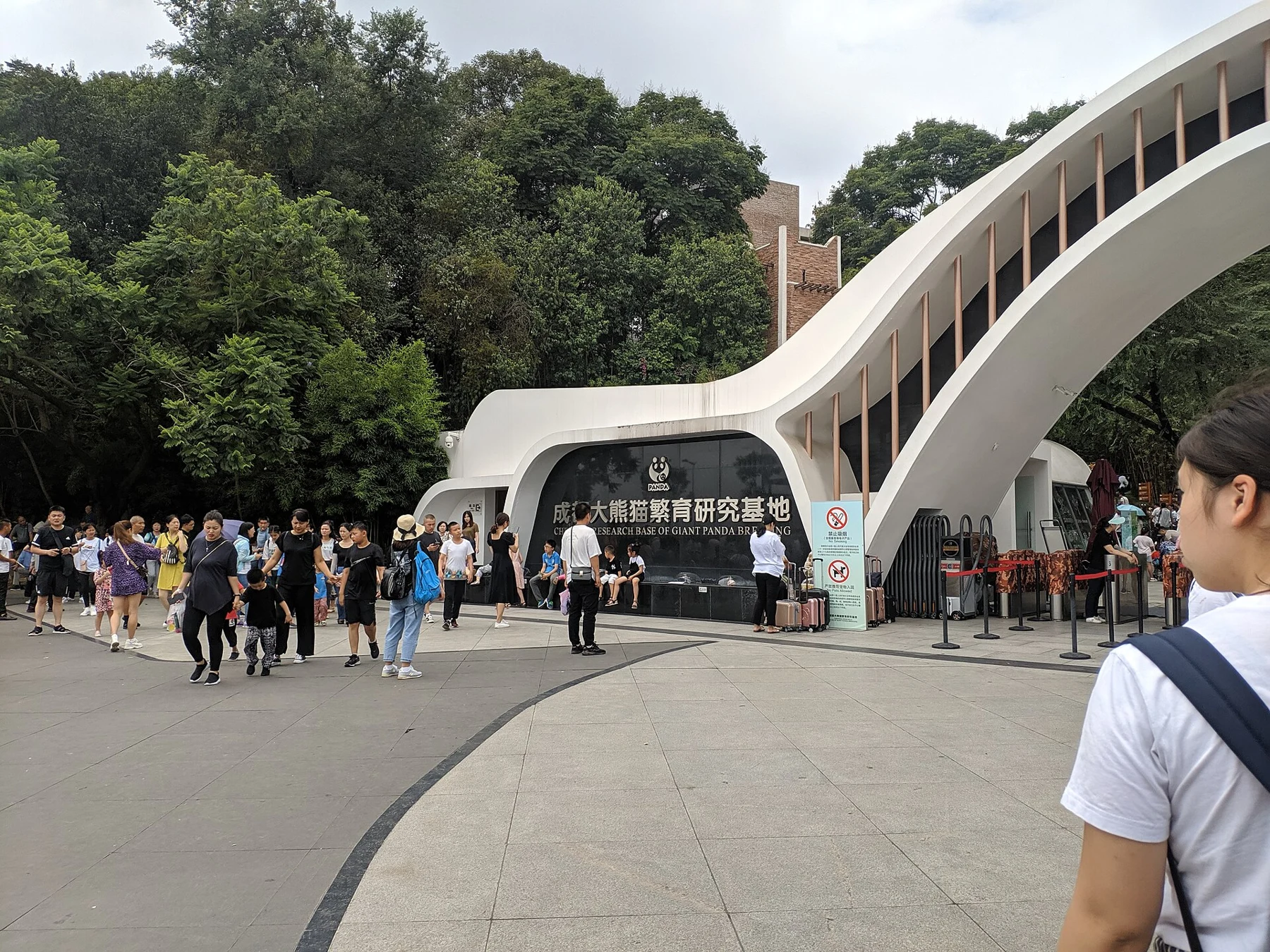 Visitors outside a curved white entrance building at the panda base