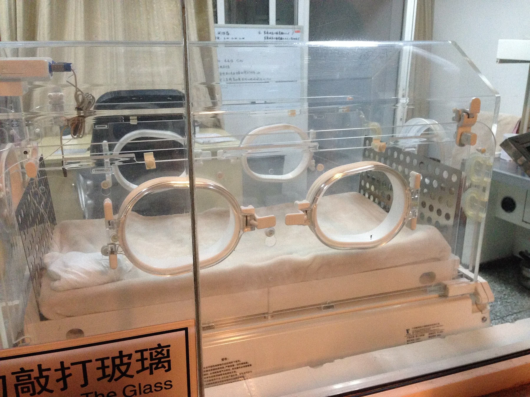Transparent incubator with circular access ports and care equipment