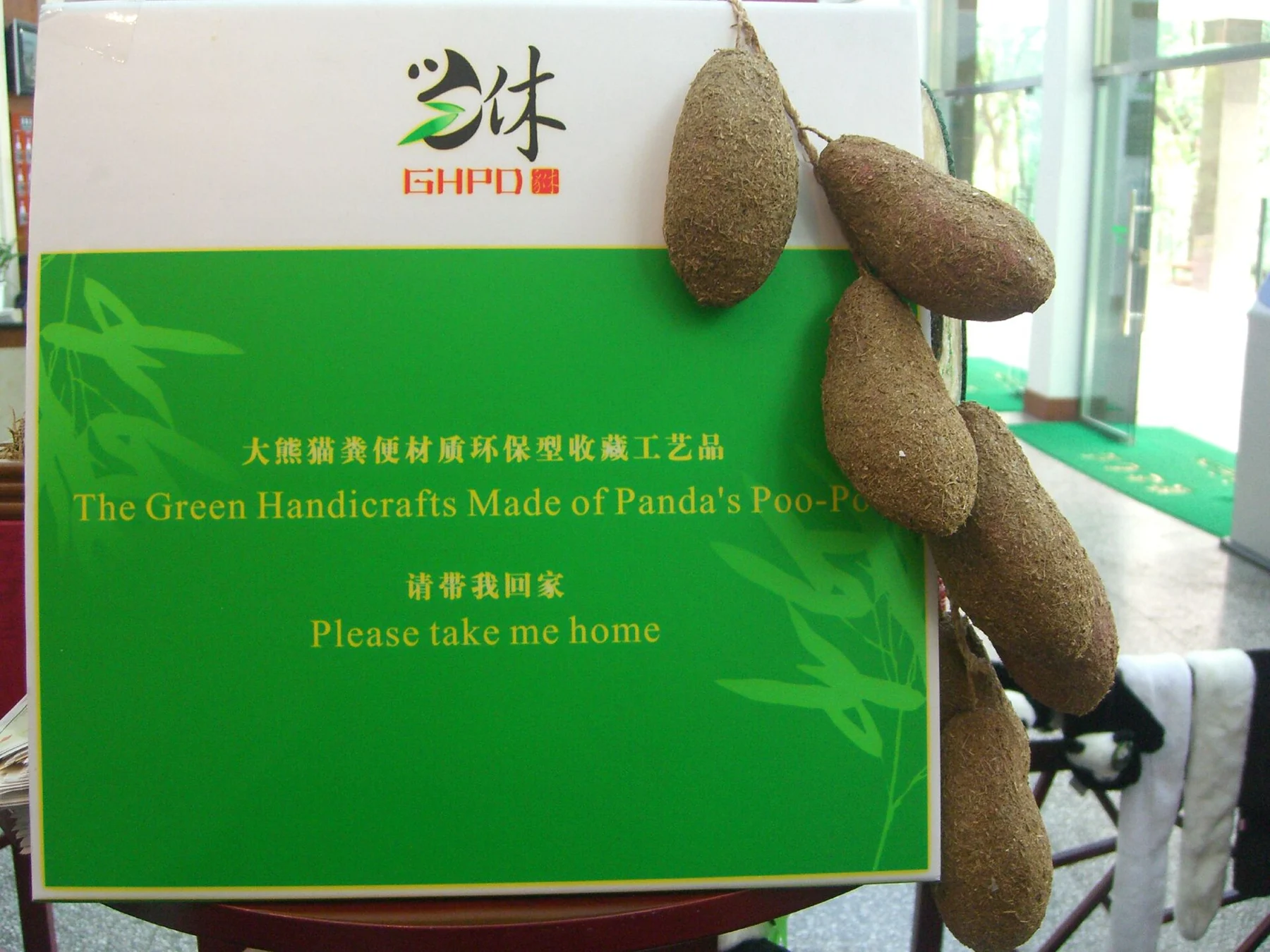 Historical museum display of brown handicraft pieces beside a bilingual panda-poo sign