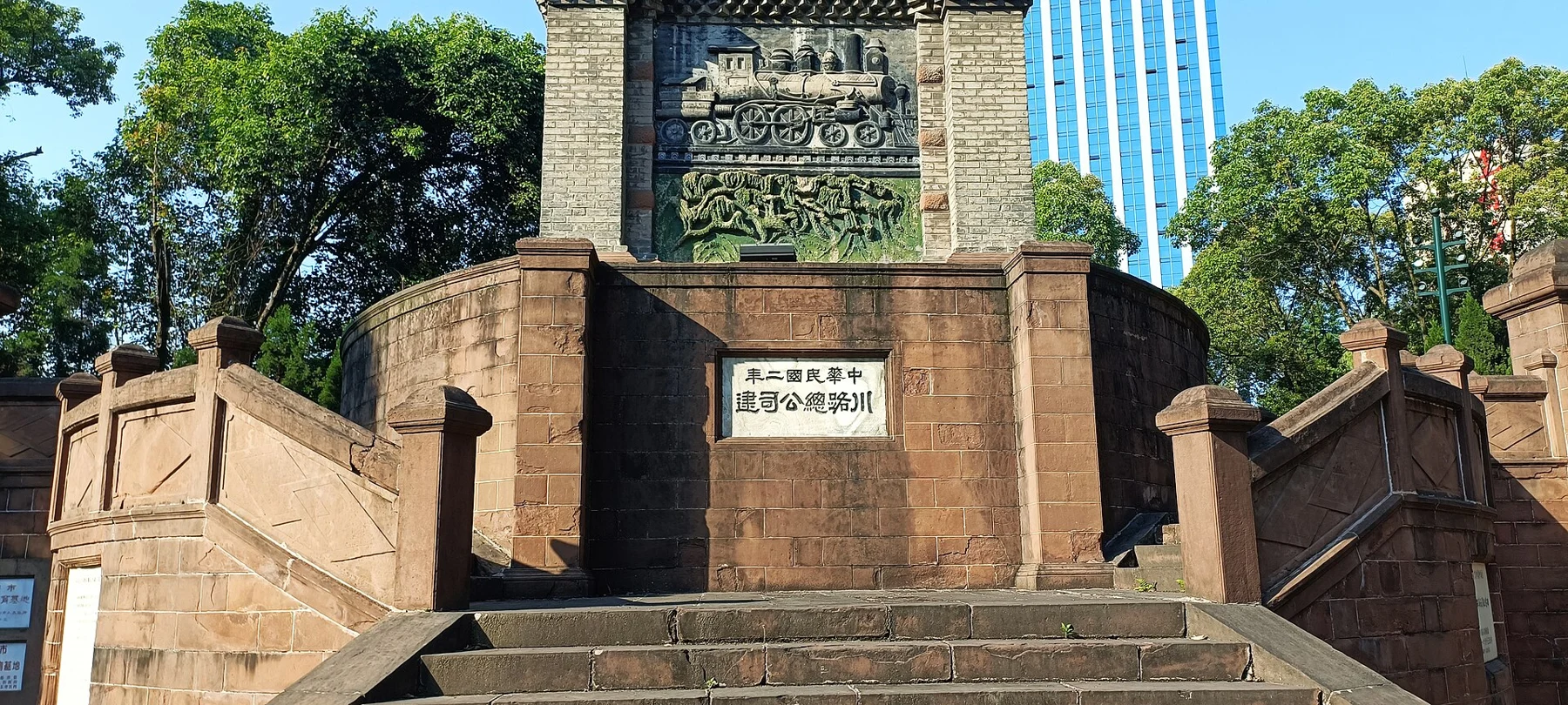 Stone steps and a foundation inscription below a relief with railway motifs.
