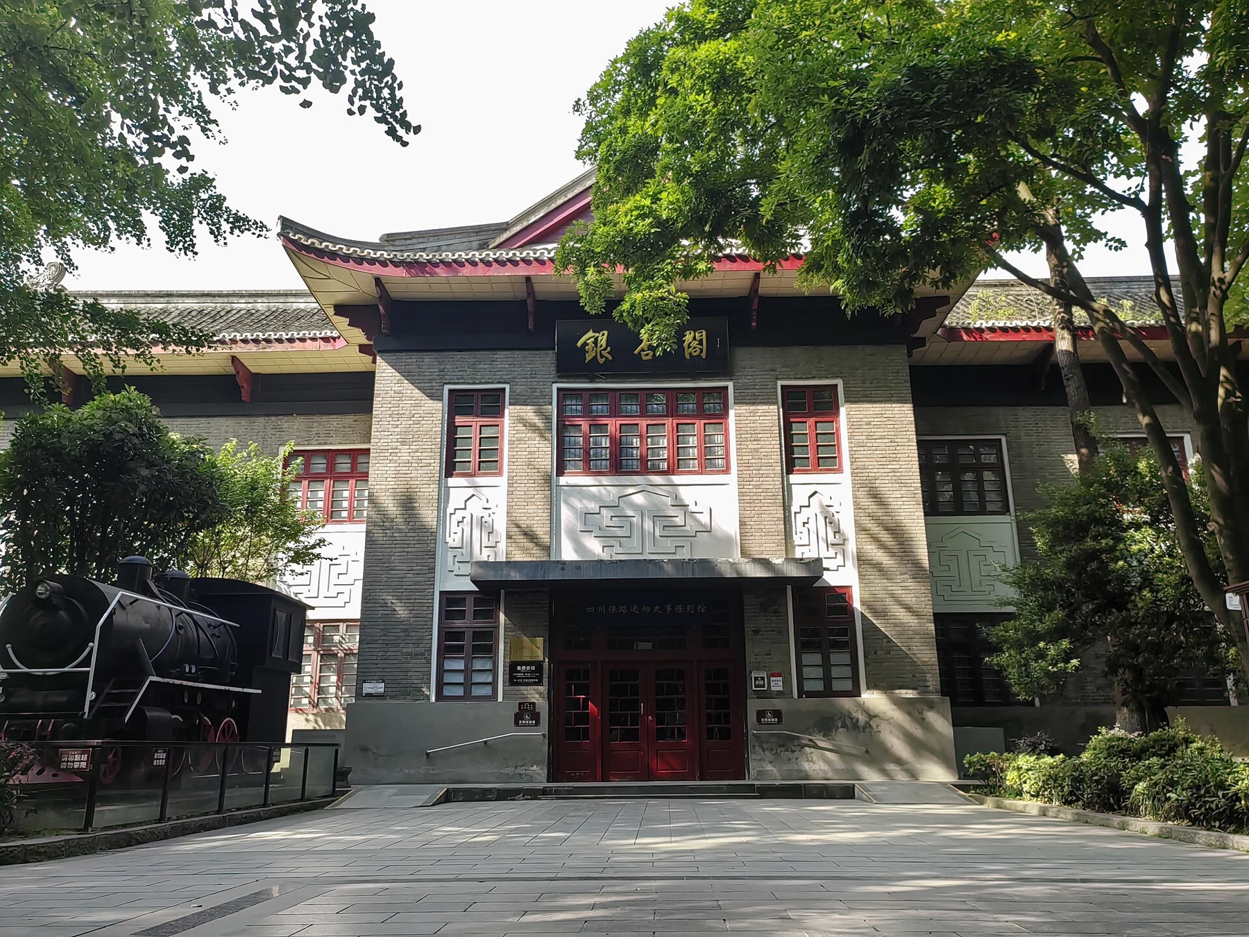 A two-storey exhibition building with Yinxing Pavilion lettering and a locomotive-shaped outdoor exhibit.