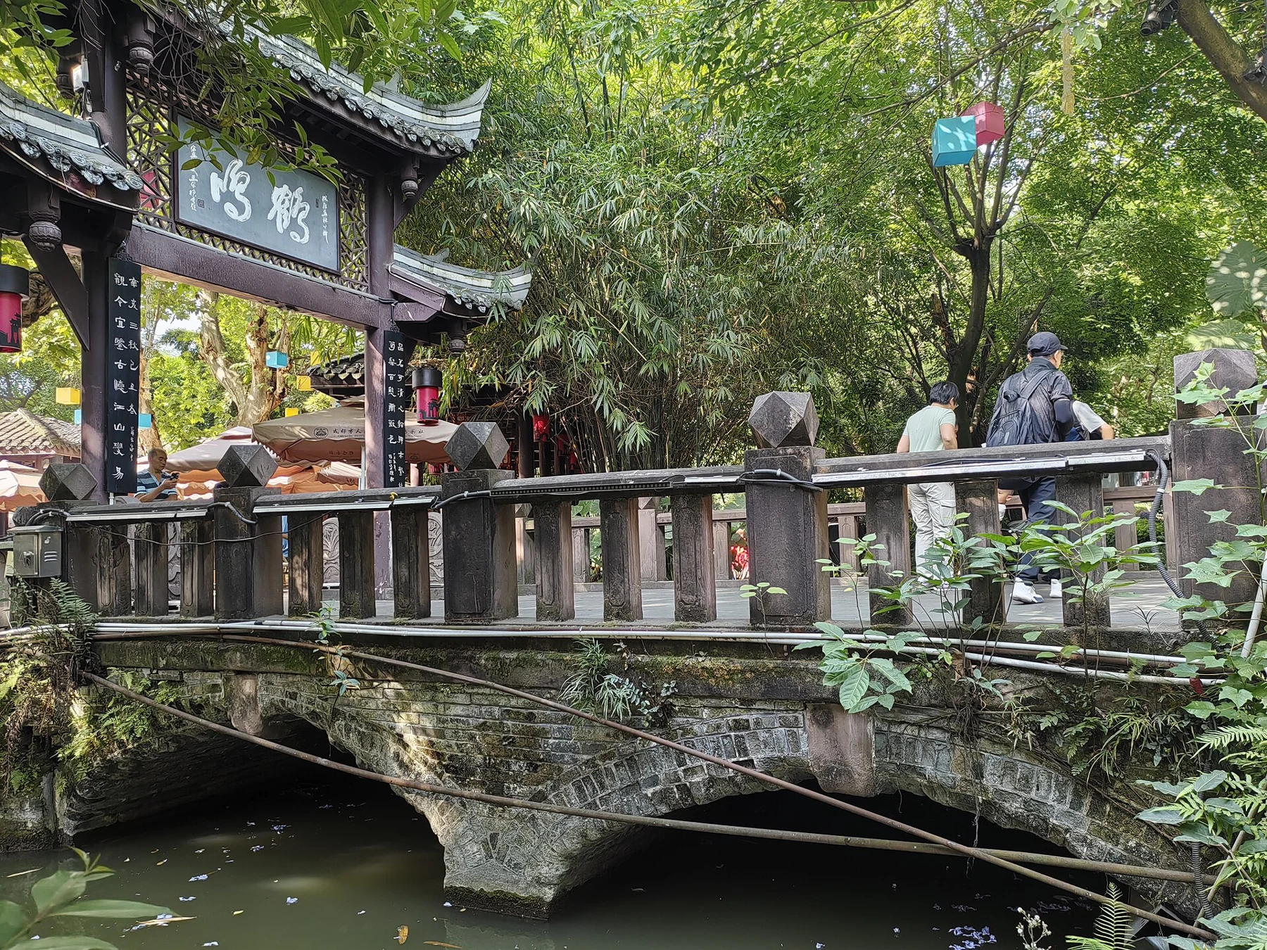 A stone-and-timber bridge beside a gateway bearing Heming characters.