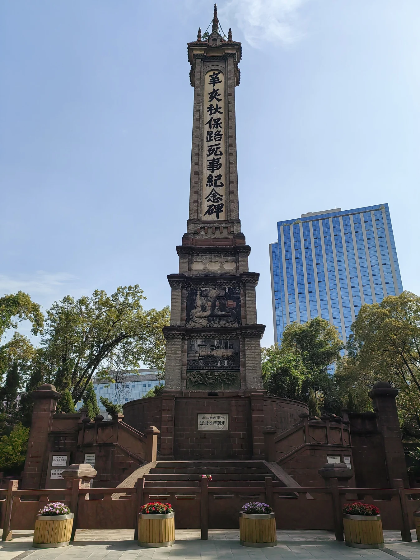 A tall square memorial tower with a long vertical Chinese inscription above a stone base.