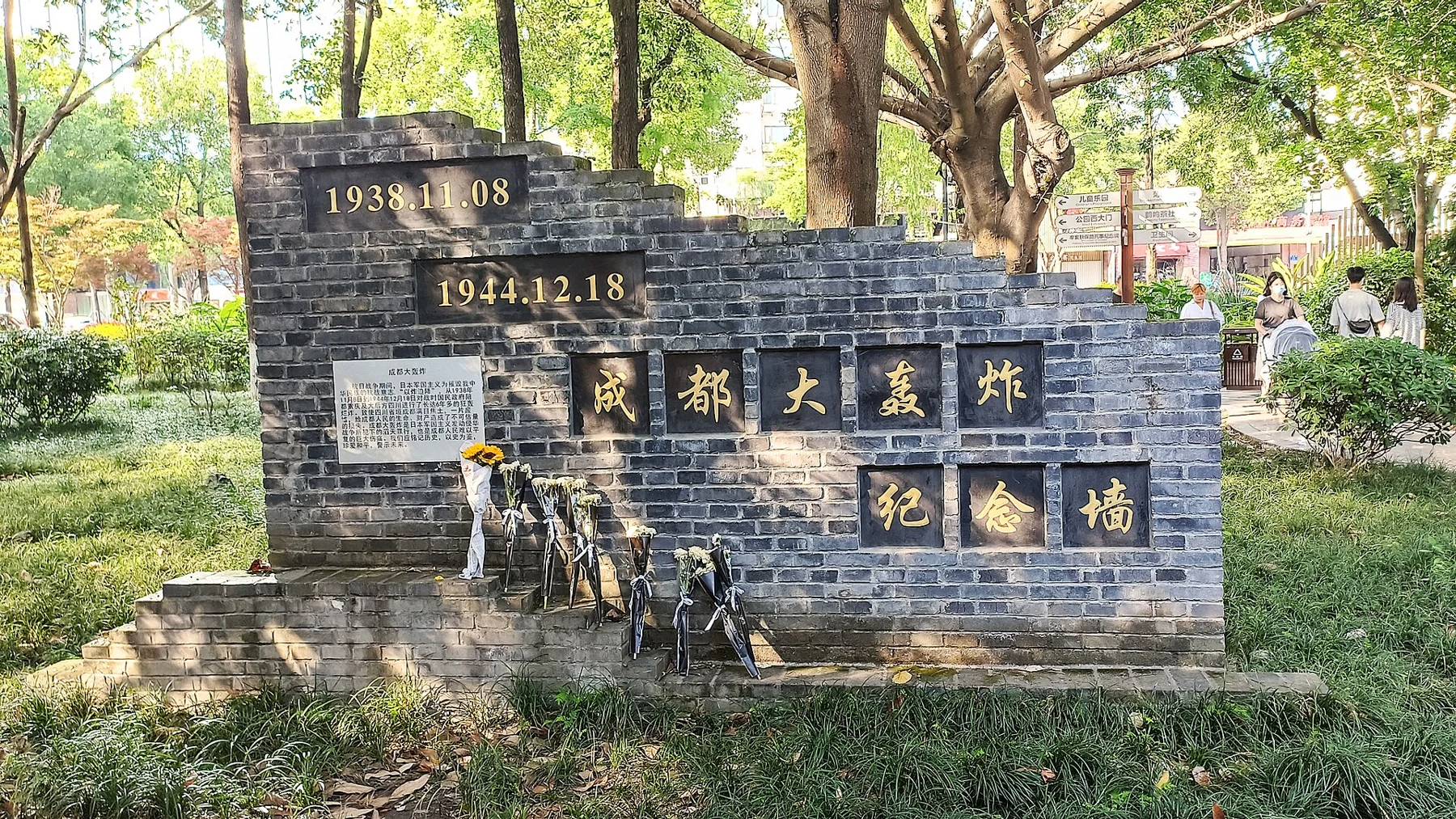 A stepped grey-brick wall bearing Chengdu bombing memorial lettering and commemorative dates.