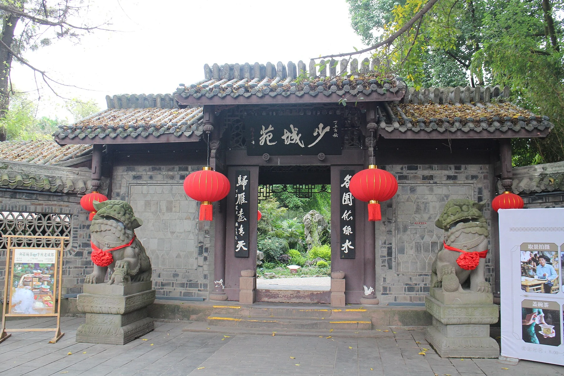 A tiled gateway with Shaocheng Yuan lettering, red lanterns and two stone lions.