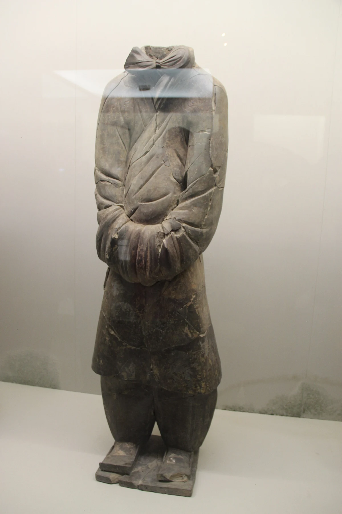 A headless K 0006 terracotta figure with hands held within its sleeves