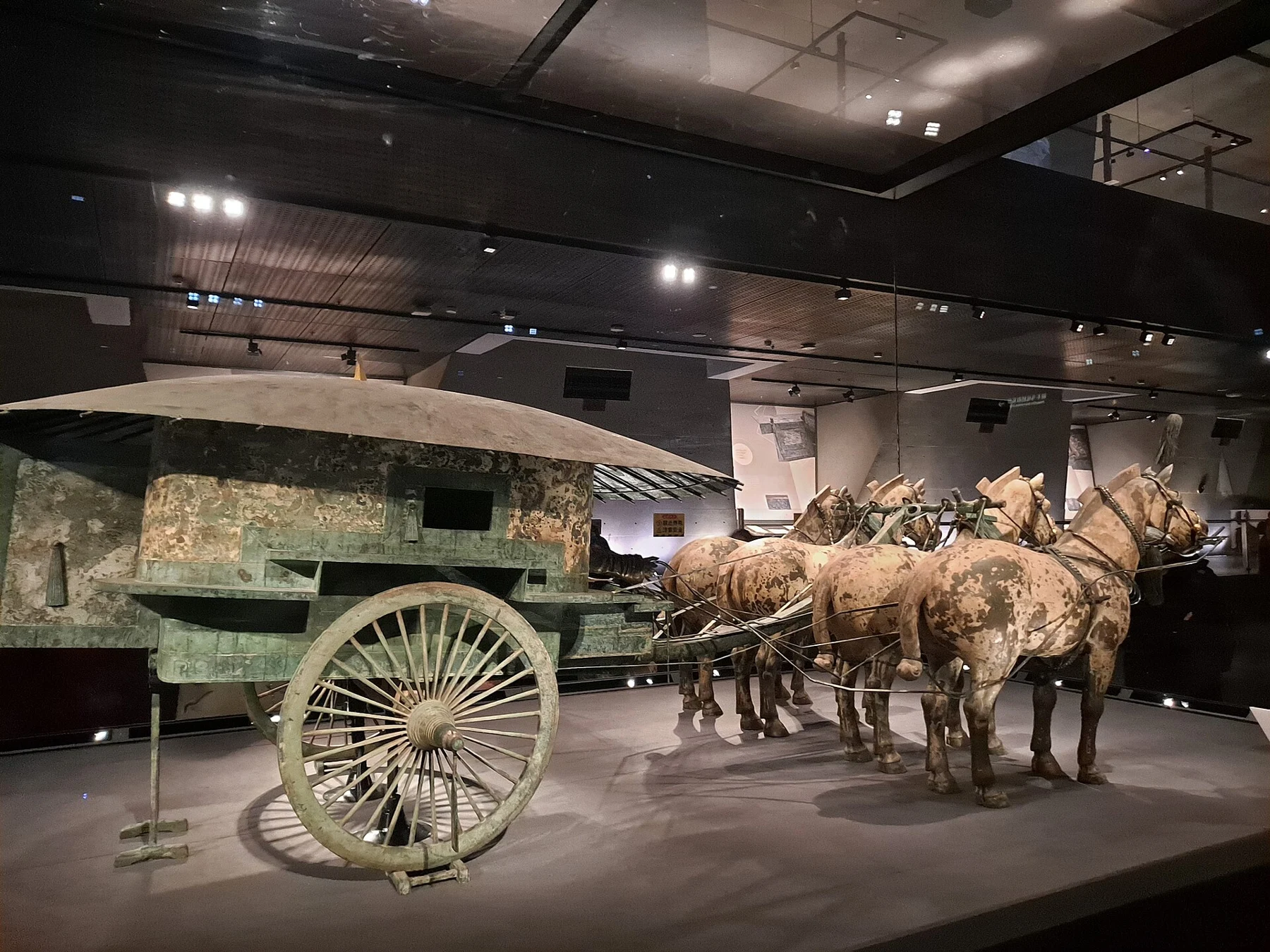 A bronze vehicle with an enclosed carriage and four horses