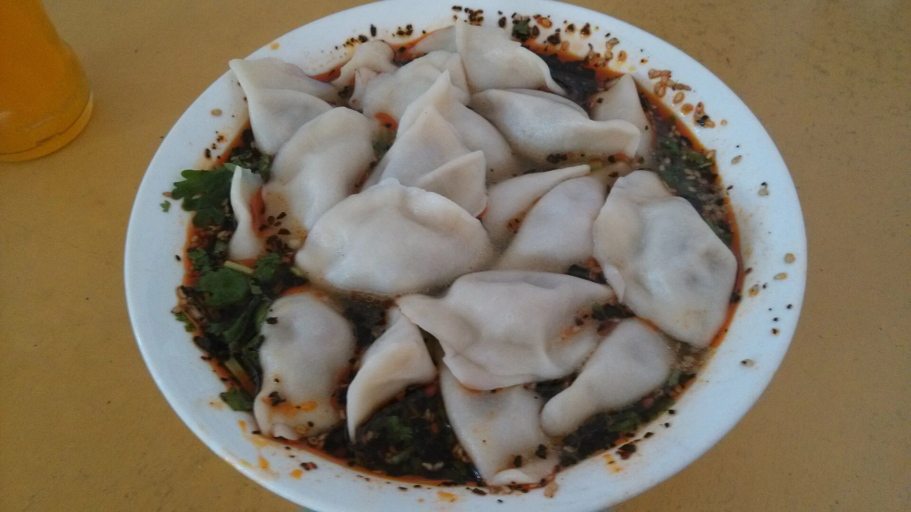 White dumplings in a dark seasoned broth with visible sesame seeds.