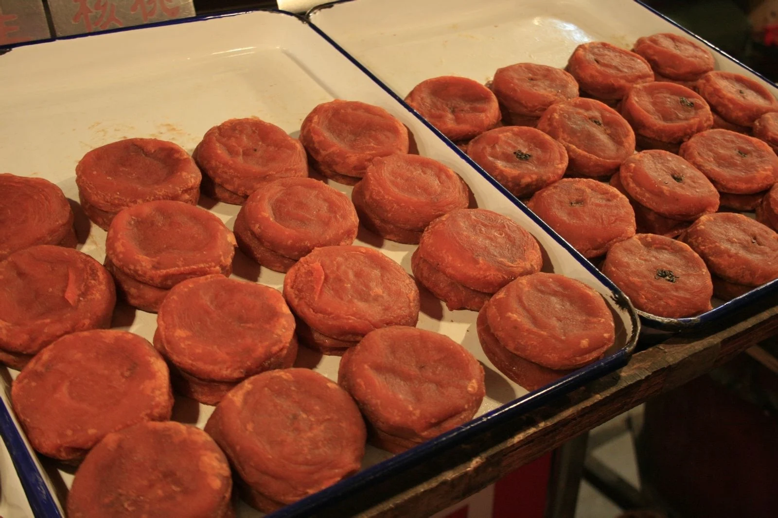 Trays of round orange-brown dough cakes, with a 椒盐 flavour sign partly visible above.