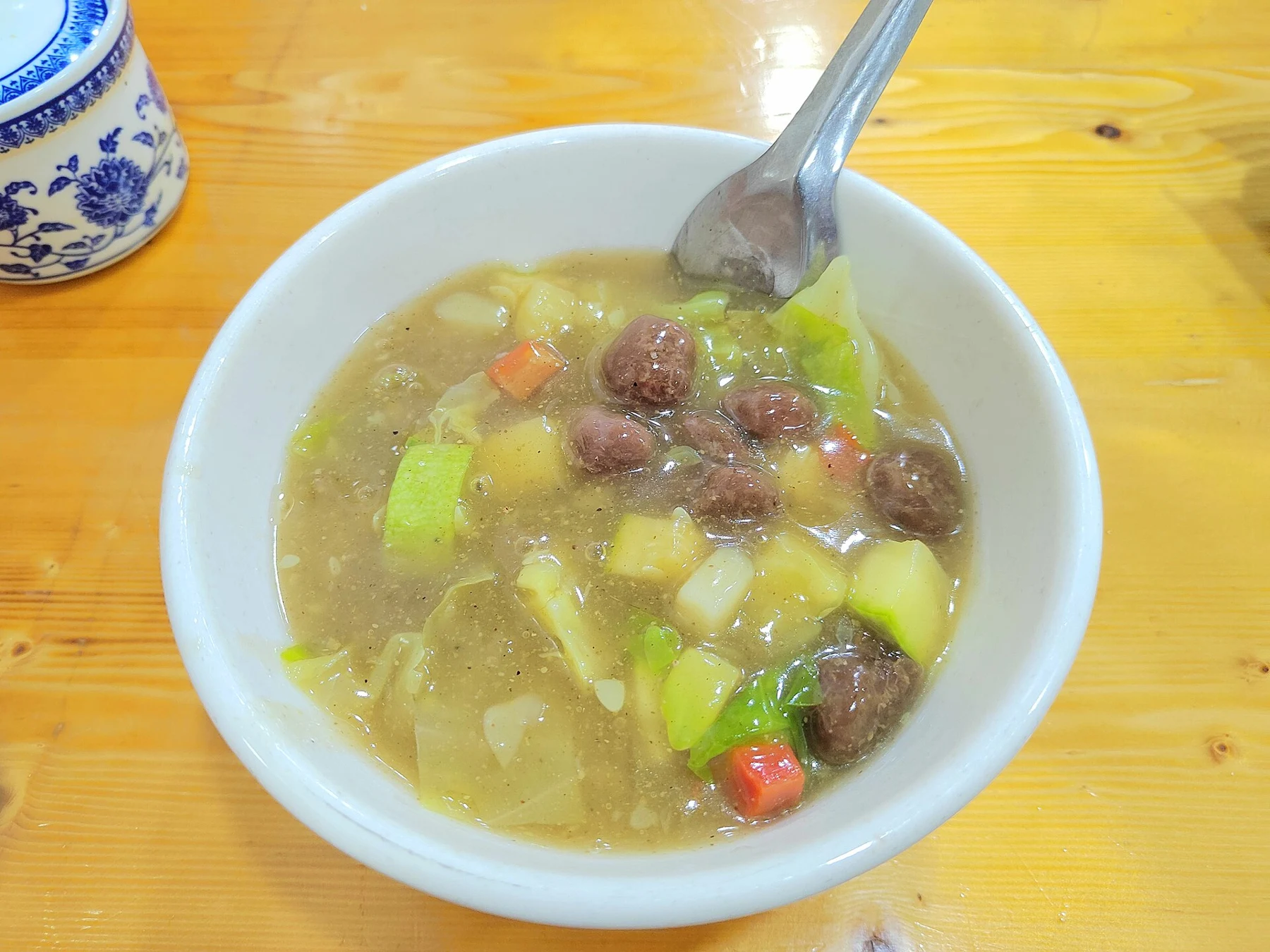 A thick pale soup with meatballs, potatoes and other vegetables.