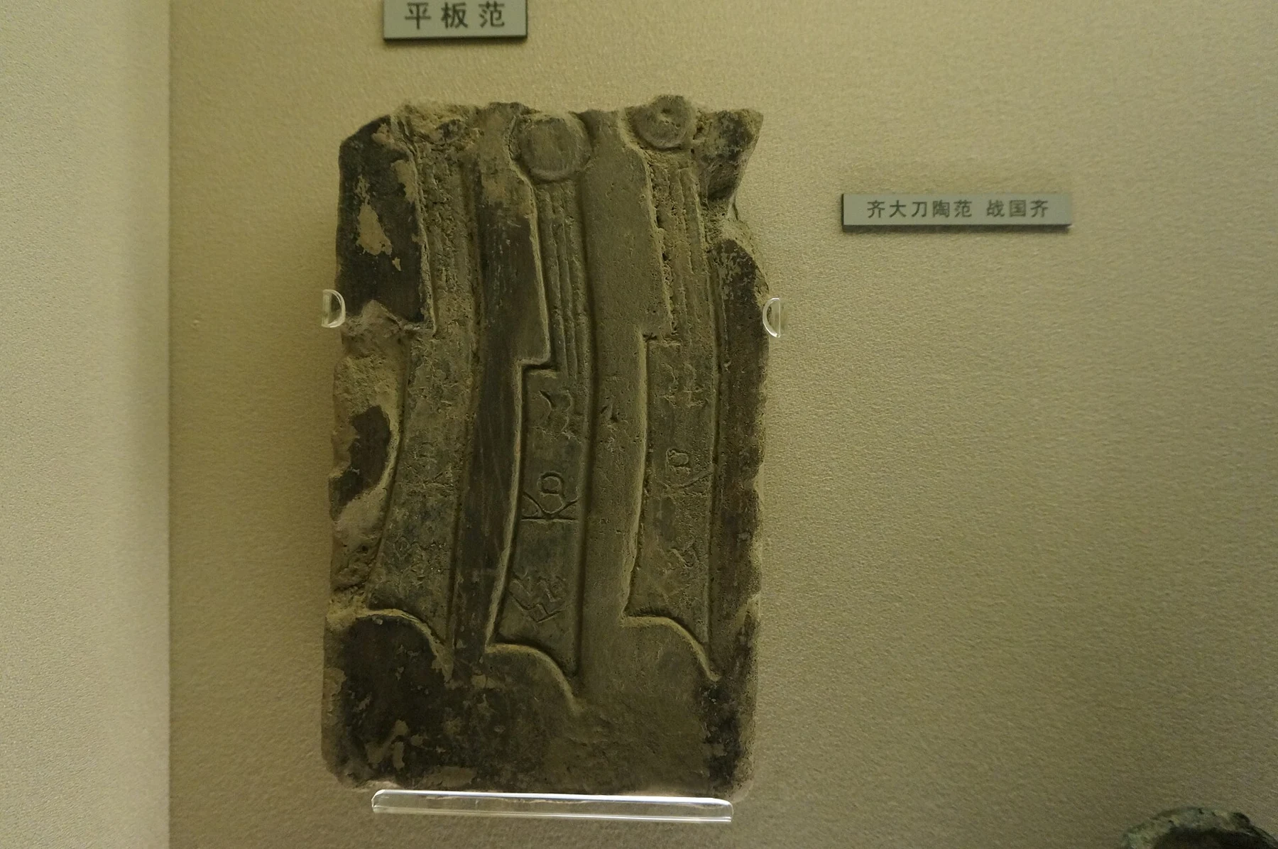 A rectangular clay mould with long recessed blade-and-handle shapes.