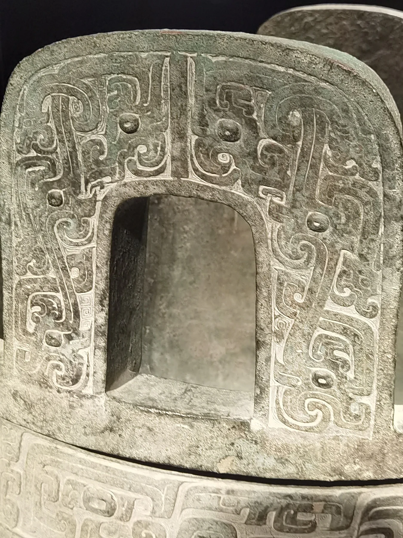 A heavy bronze leg with a recessed opening and a stylised animal-mask design.