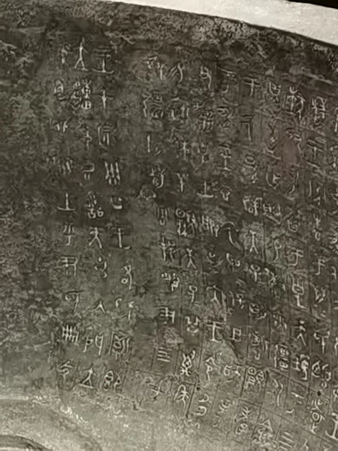 Rows of cast ancient characters on a curved bronze surface.
