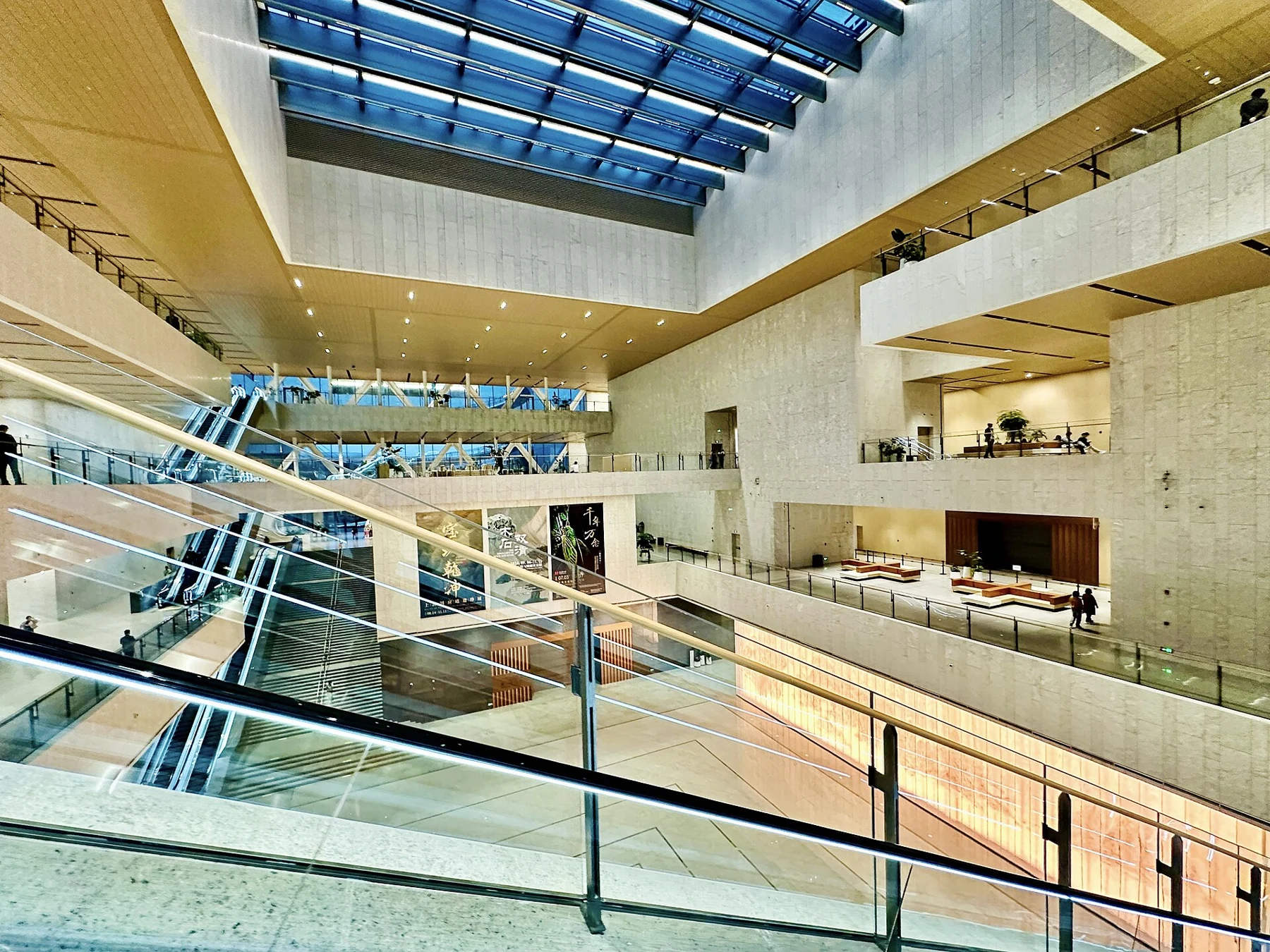 A bright multi-level museum interior with glass balustrades, bridges and a glazed roof.