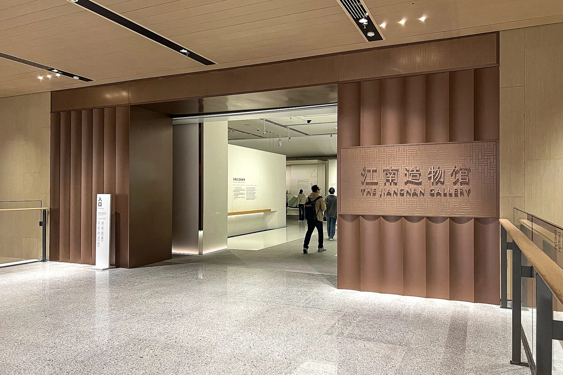 A warm timber-lined gallery entrance with the 江南造物馆 and The Jiangnan Gallery signs.