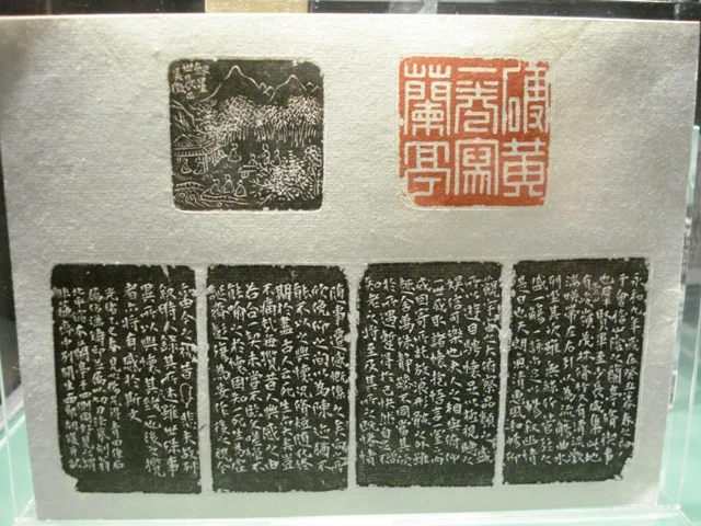 Black rubbed inscriptions and a red square seal impression mounted together in a display.