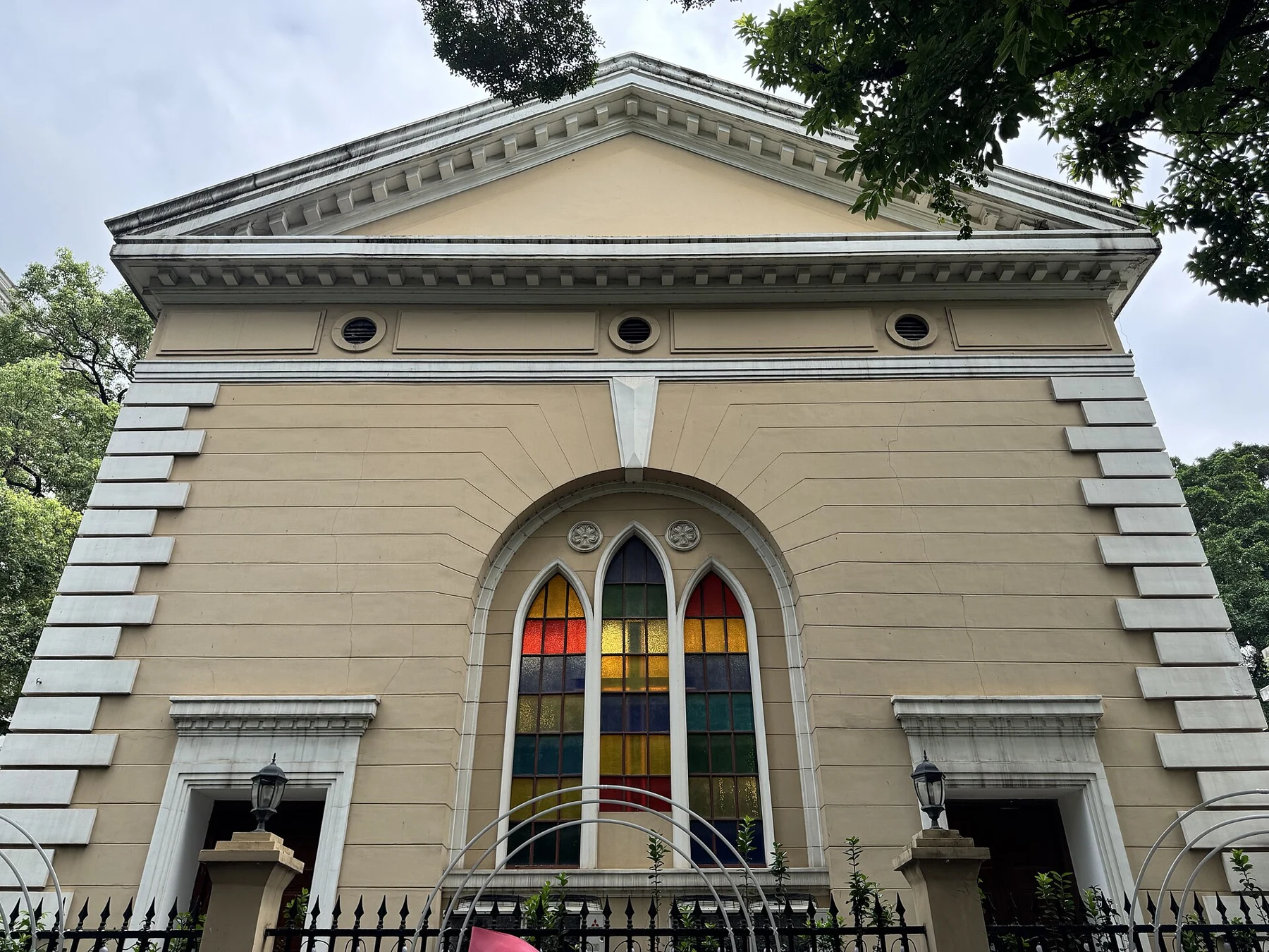 Coloured pointed window in the yellow exterior wall of Christ Church of Shameen.