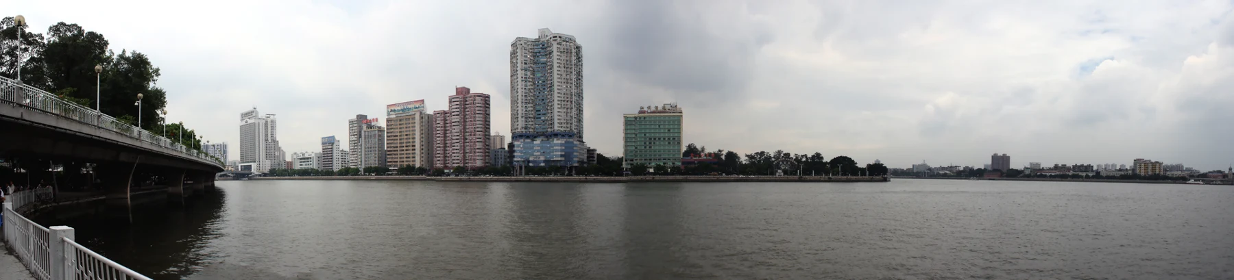 Wide older view over the river from Shamian, with buildings across the water.