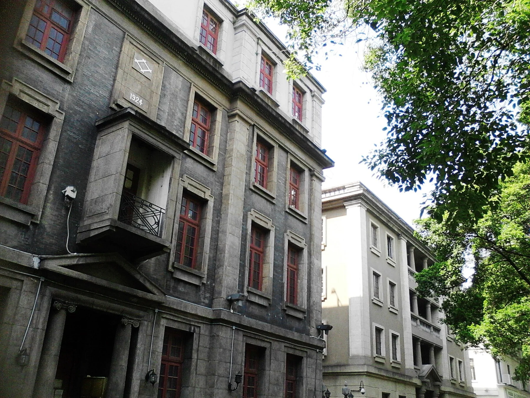 Grey and pale building fronts with projecting details beside a street.
