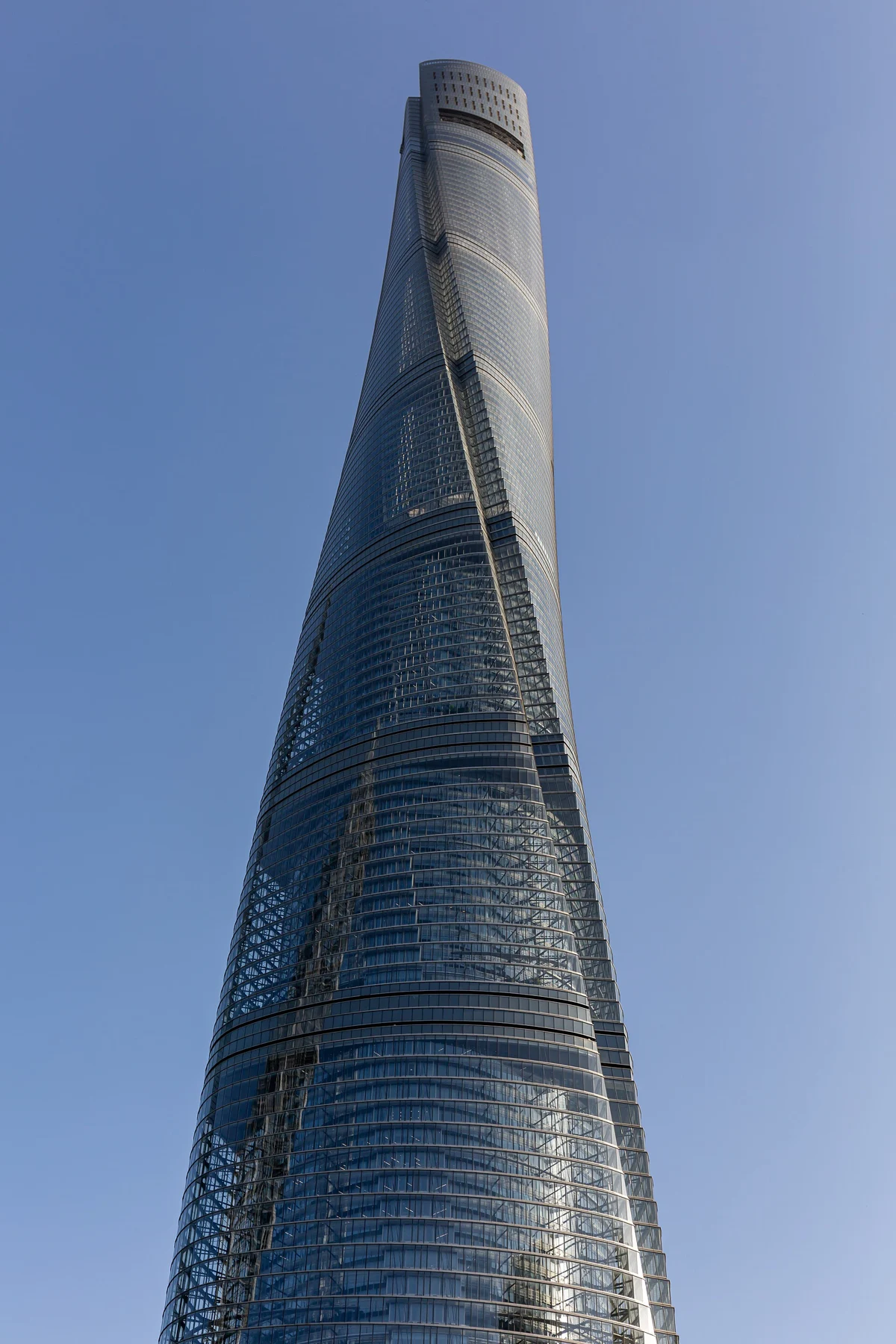 A section of the tower’s rounded skin and diagonal profile against blue sky.