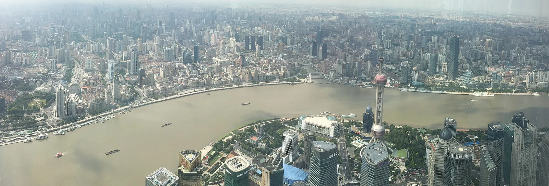 Broad horizontal river-and-city panorama in recorded daytime haze.