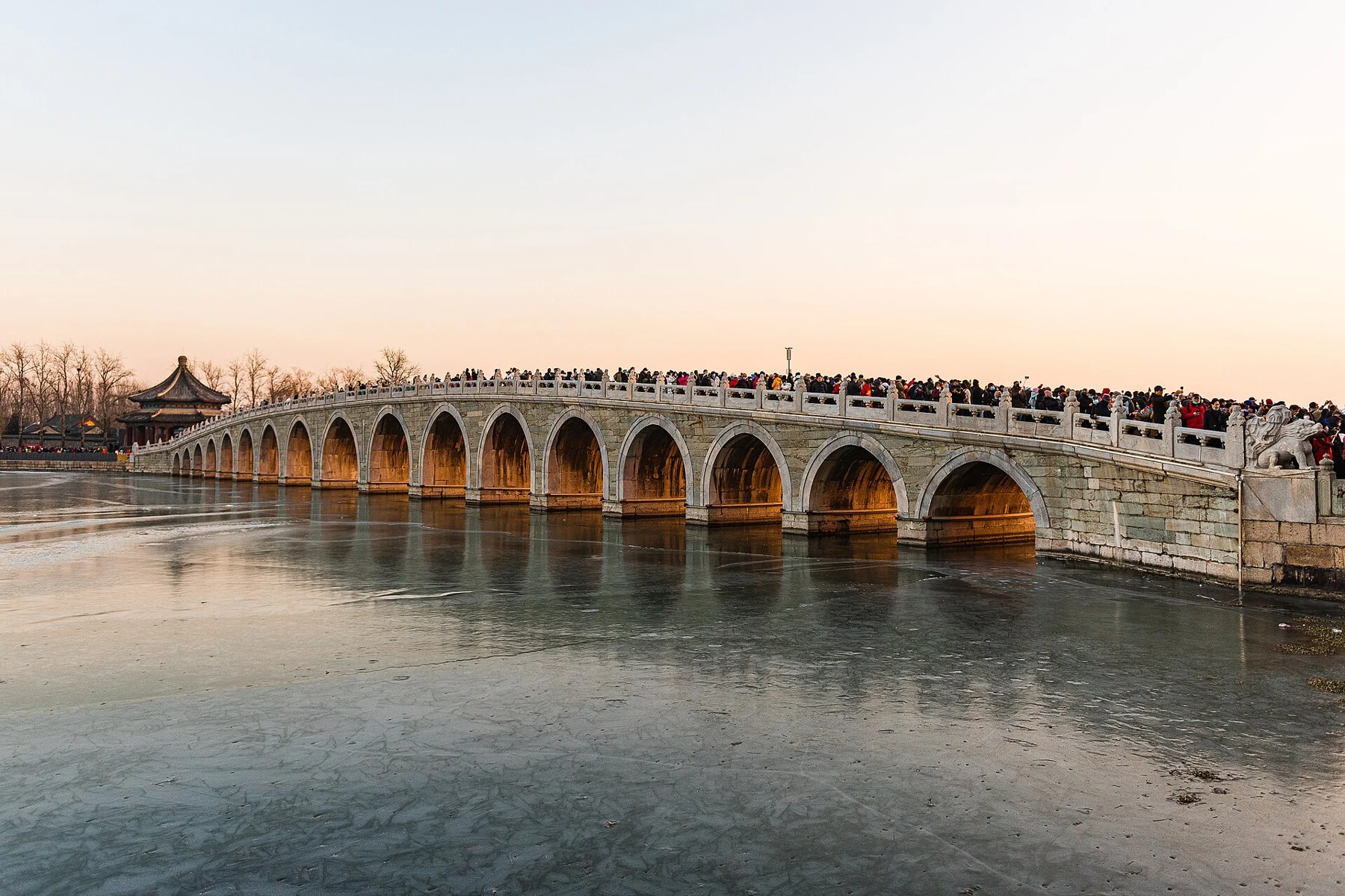Warm evening light illuminating the arches of the Seventeen-Arch Bridge across the lake.