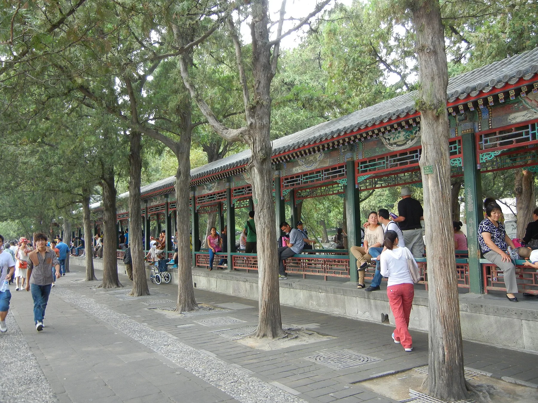 Visitors beside the Long Corridor, with its covered roof and painted panels visible through the columns.