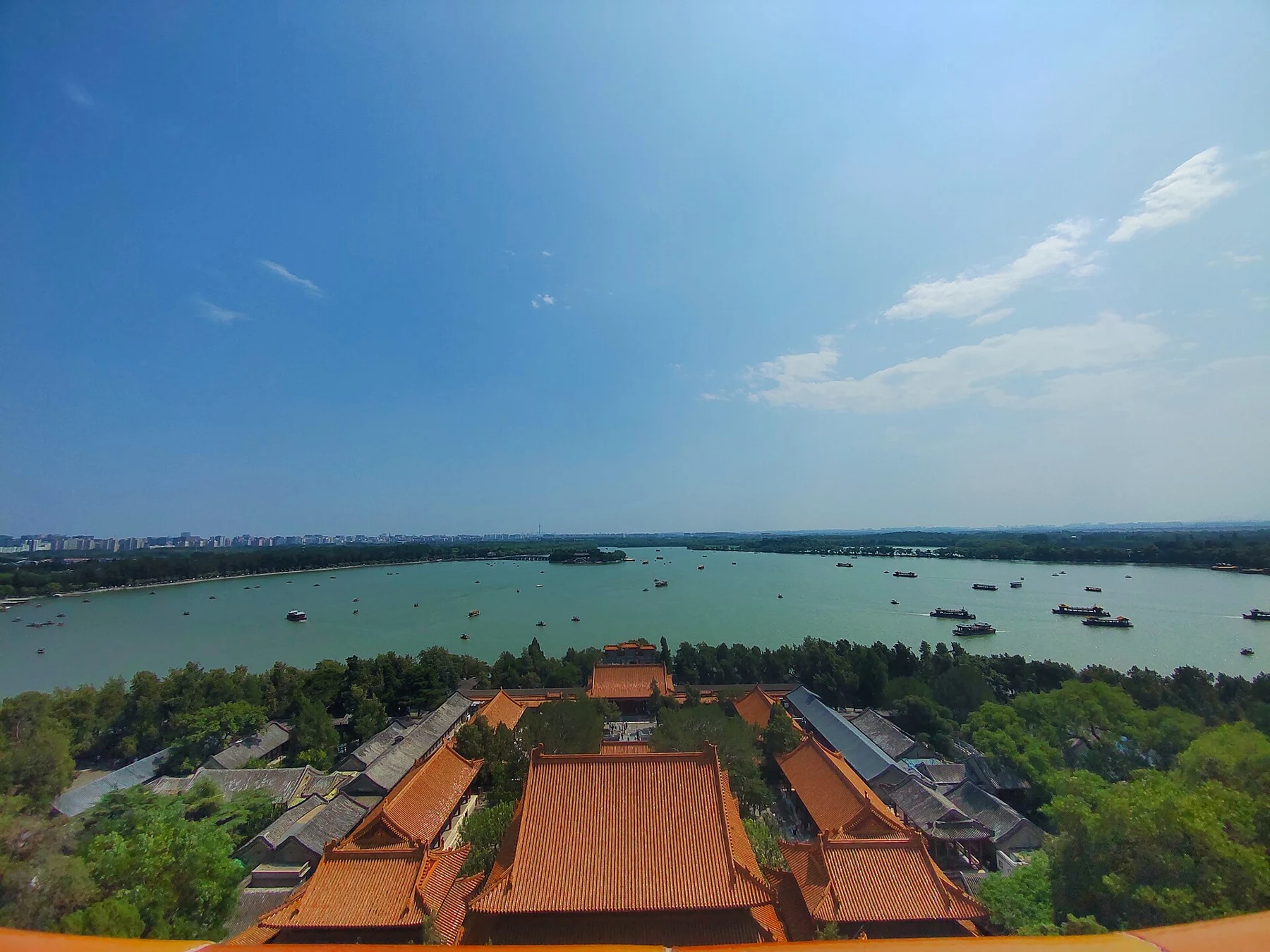 Palace roofs below an elevated viewpoint, with Kunming Lake and small boats beyond.
