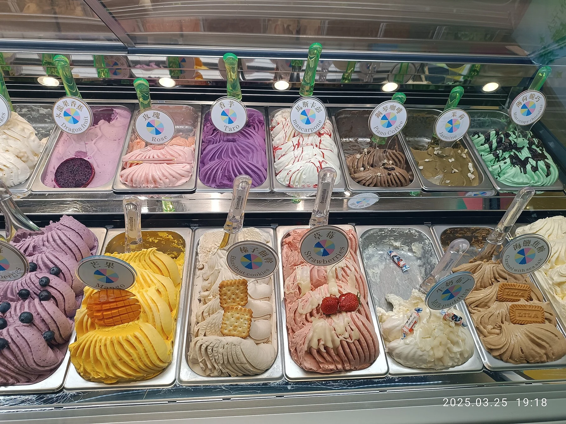 Rows of colourful frozen-dessert trays behind a glass counter with round flavour labels.
