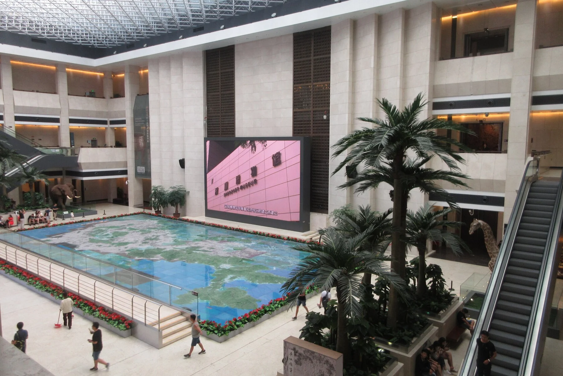 Geographical model and planting surrounded by several levels of museum galleries