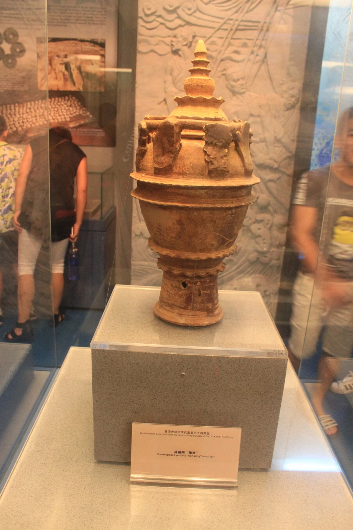 Tall brown-glazed soul jar with a tiered upper part and small sculptural details