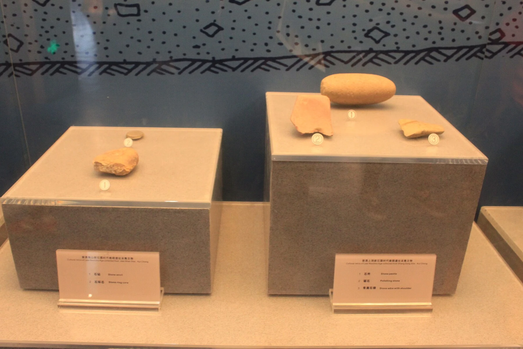 Several differently shaped stone implements mounted above bilingual labels