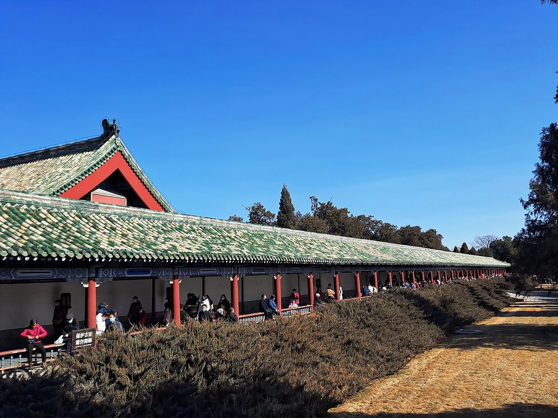 The green-tiled roof and repeated bays of the Long Corridor beside winter vegetation.