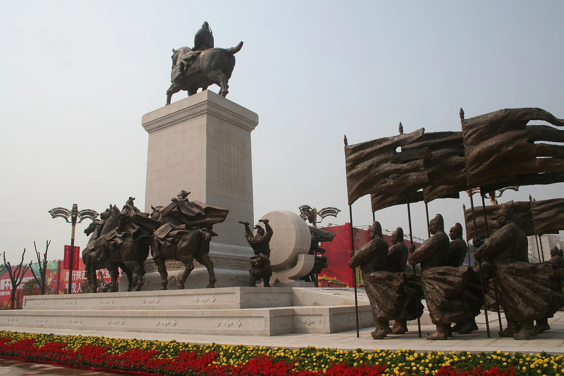 A mounted figure high on a column, with horsemen, standing figures and flowing banners below.