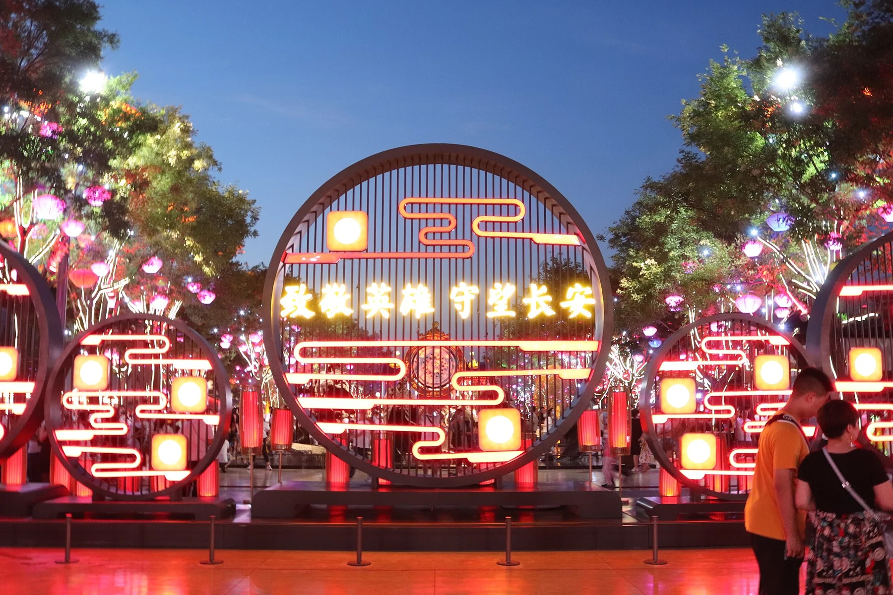 Three red-and-gold circular decorations with the words 祝福神州 守望长安 in the central display.