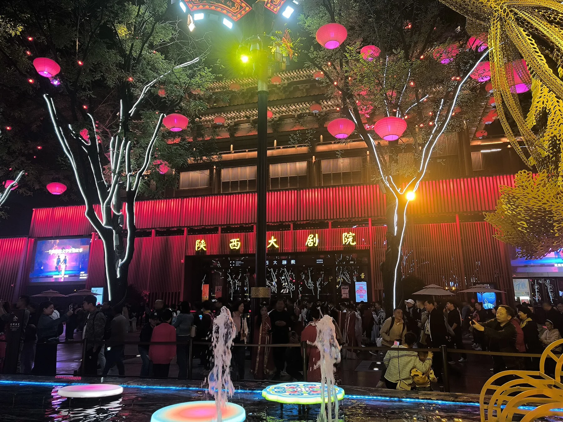 The red-lit 陕西大剧院 facade with visitors and lanterns in front.