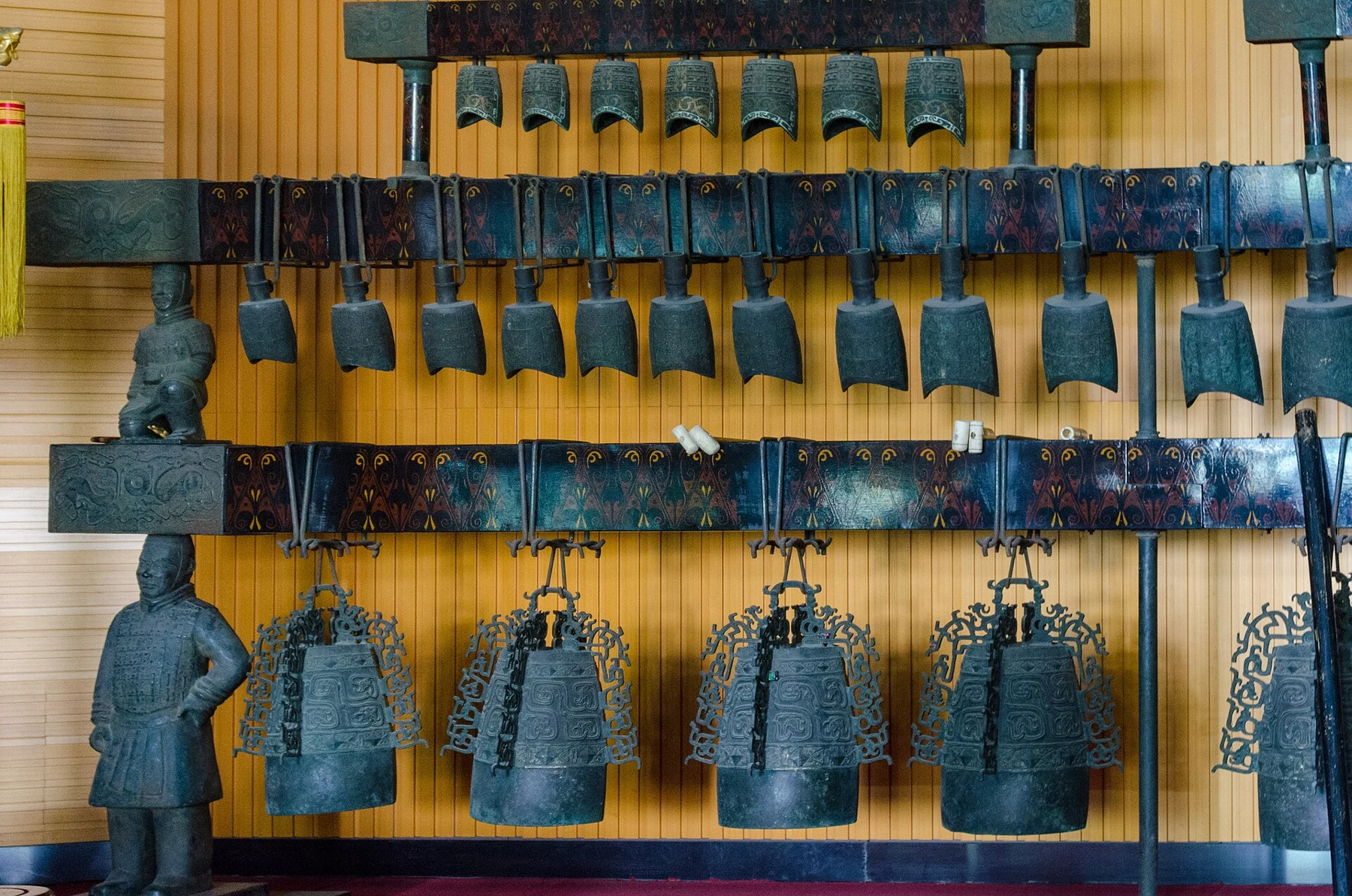 Rows of hanging chime bells in an older museum instrument display.