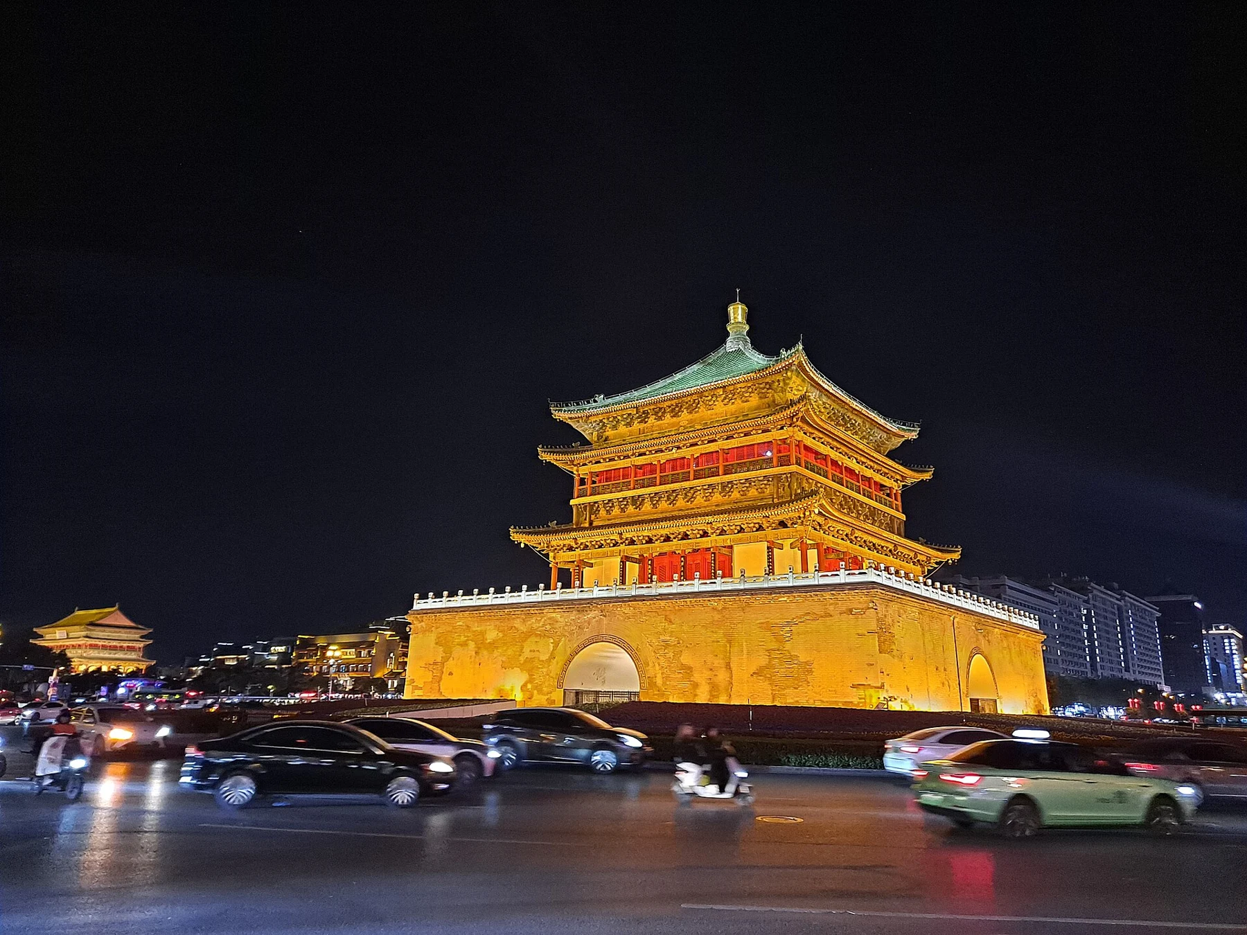 The illuminated Bell Tower seen beyond cars on the circular road.