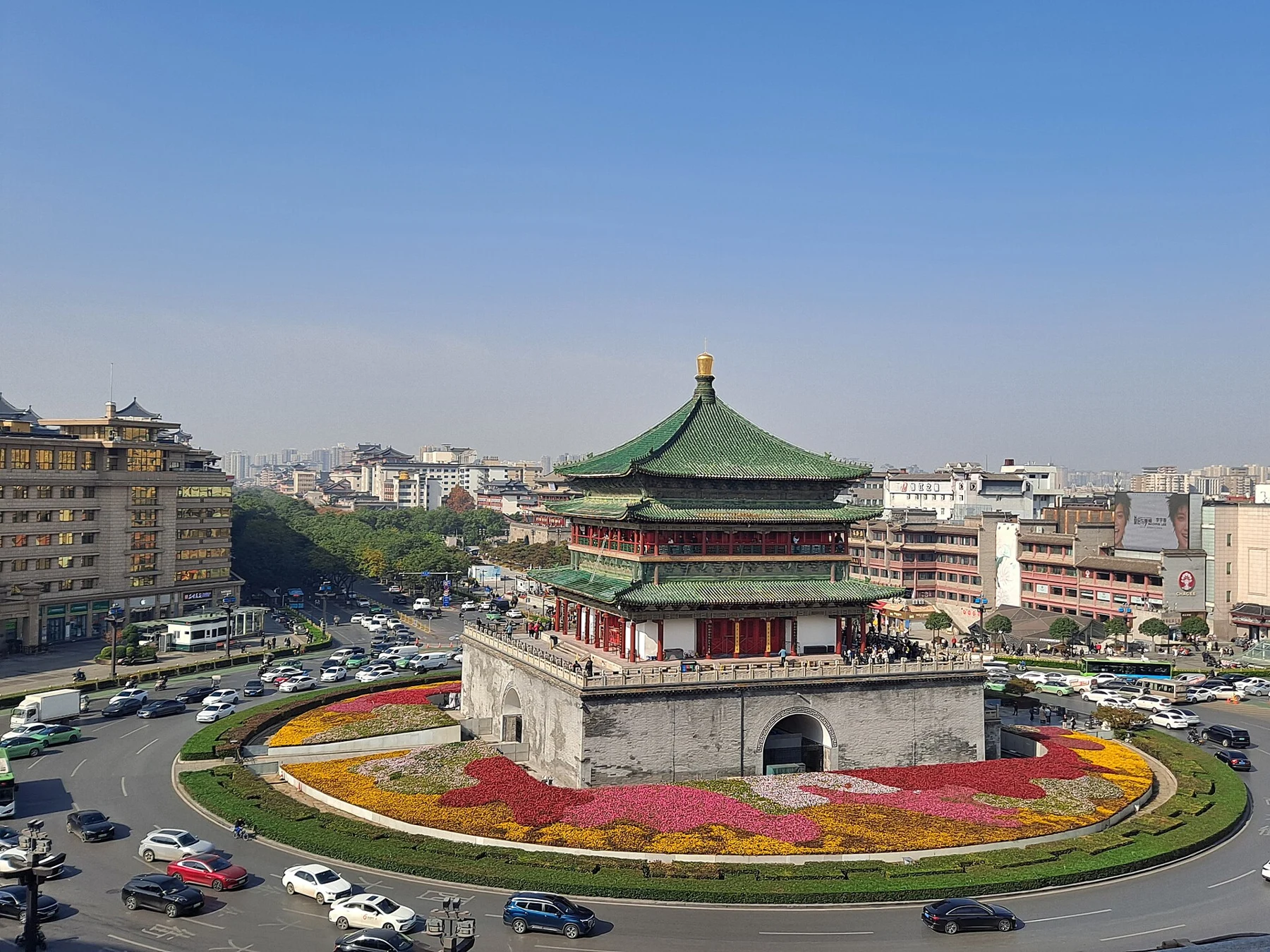 The Bell Tower at the centre of a circular road with traffic and city buildings.