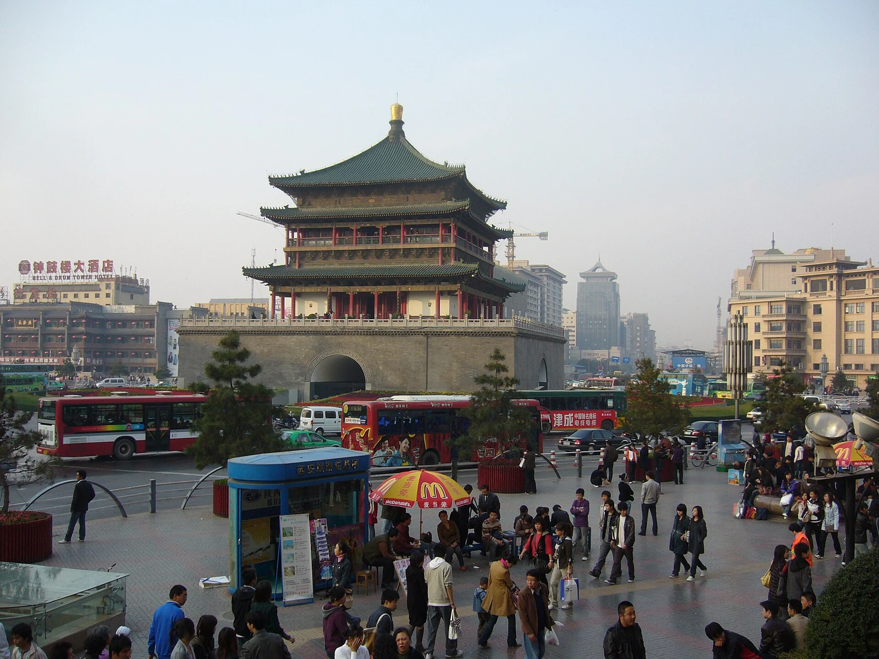 An archival street-level view towards the Bell Tower with pedestrians and vehicles.