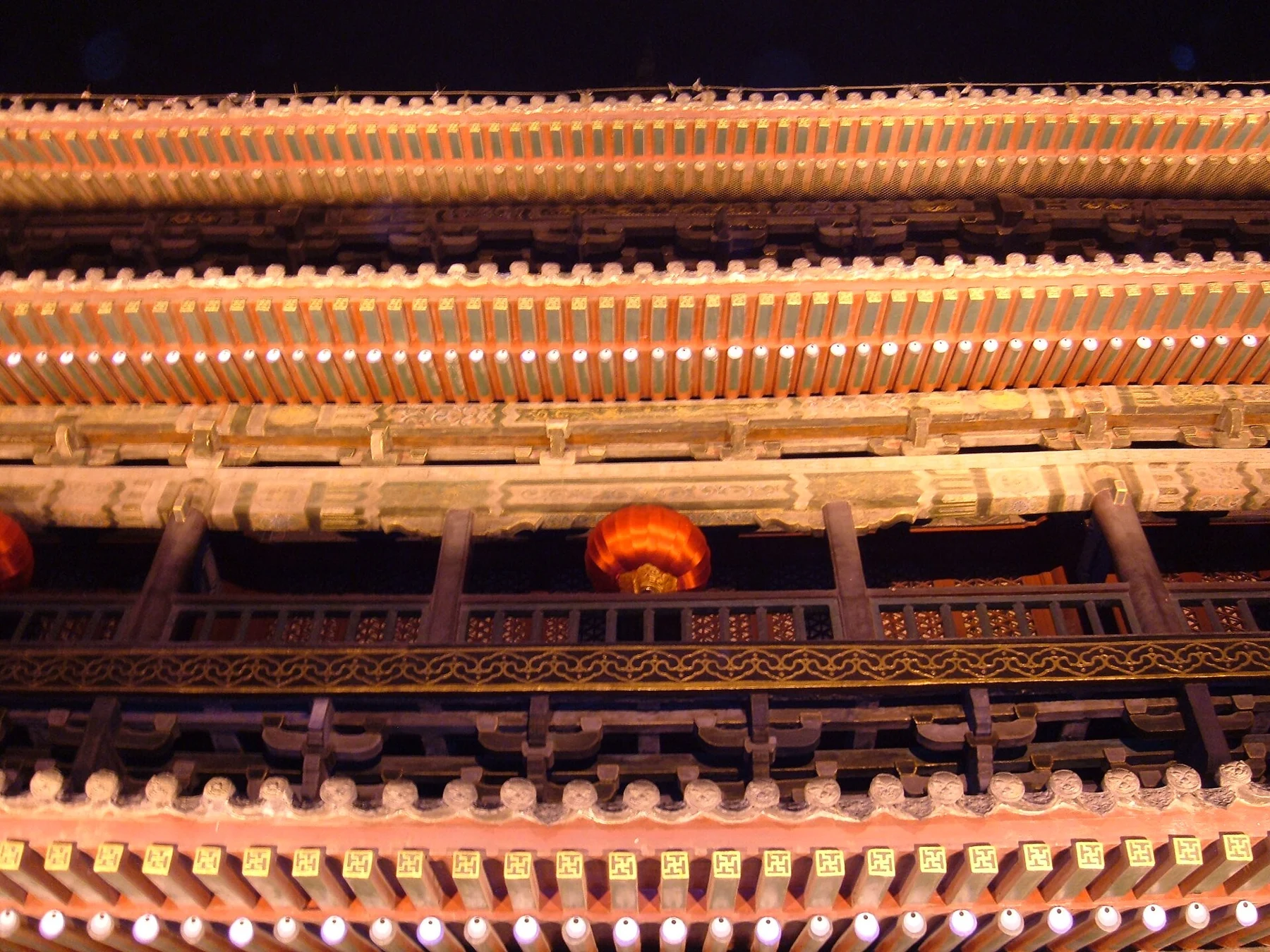 Rows of illuminated brackets and painted eaves on the Drum Tower facade at night.